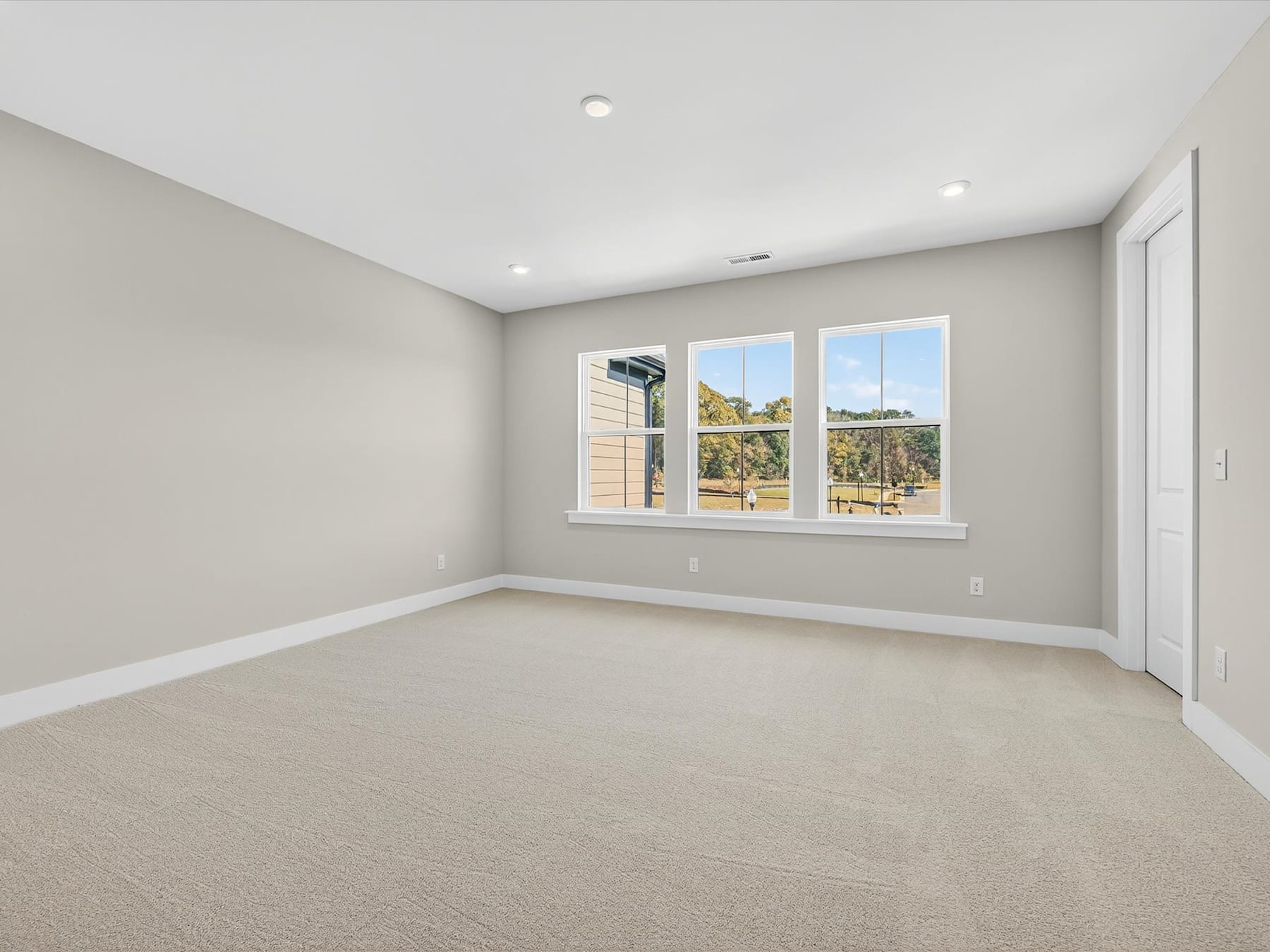 An empty, well-lit room with large windows overlooking a scenic outdoor landscape.