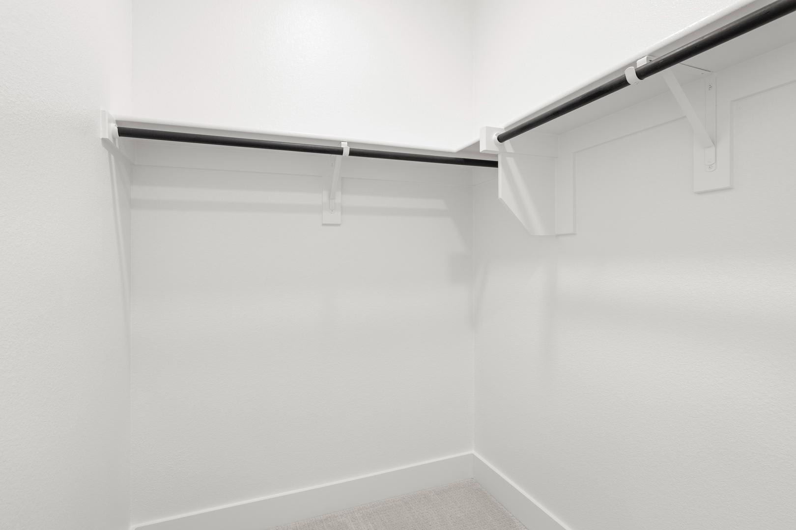 A white, minimalist closet with shelves and a hanging rod, creating a clean and organized storage space.