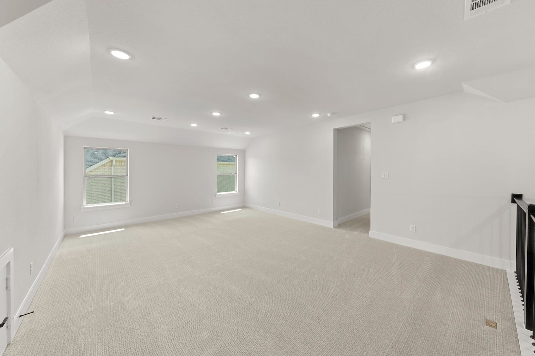 A spacious, well-lit room with white walls, recessed lighting, and a carpeted floor.
