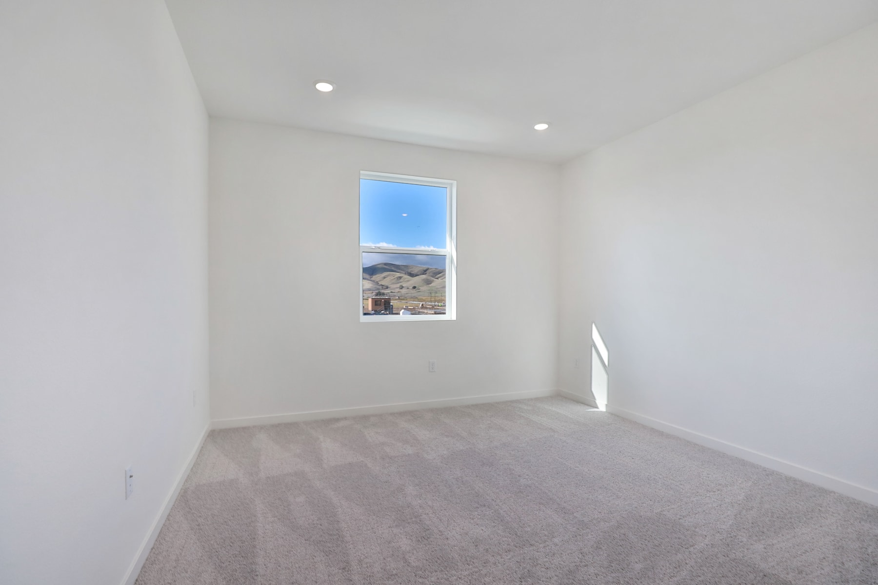 A bright, empty room with a window overlooking a scenic landscape in the background.