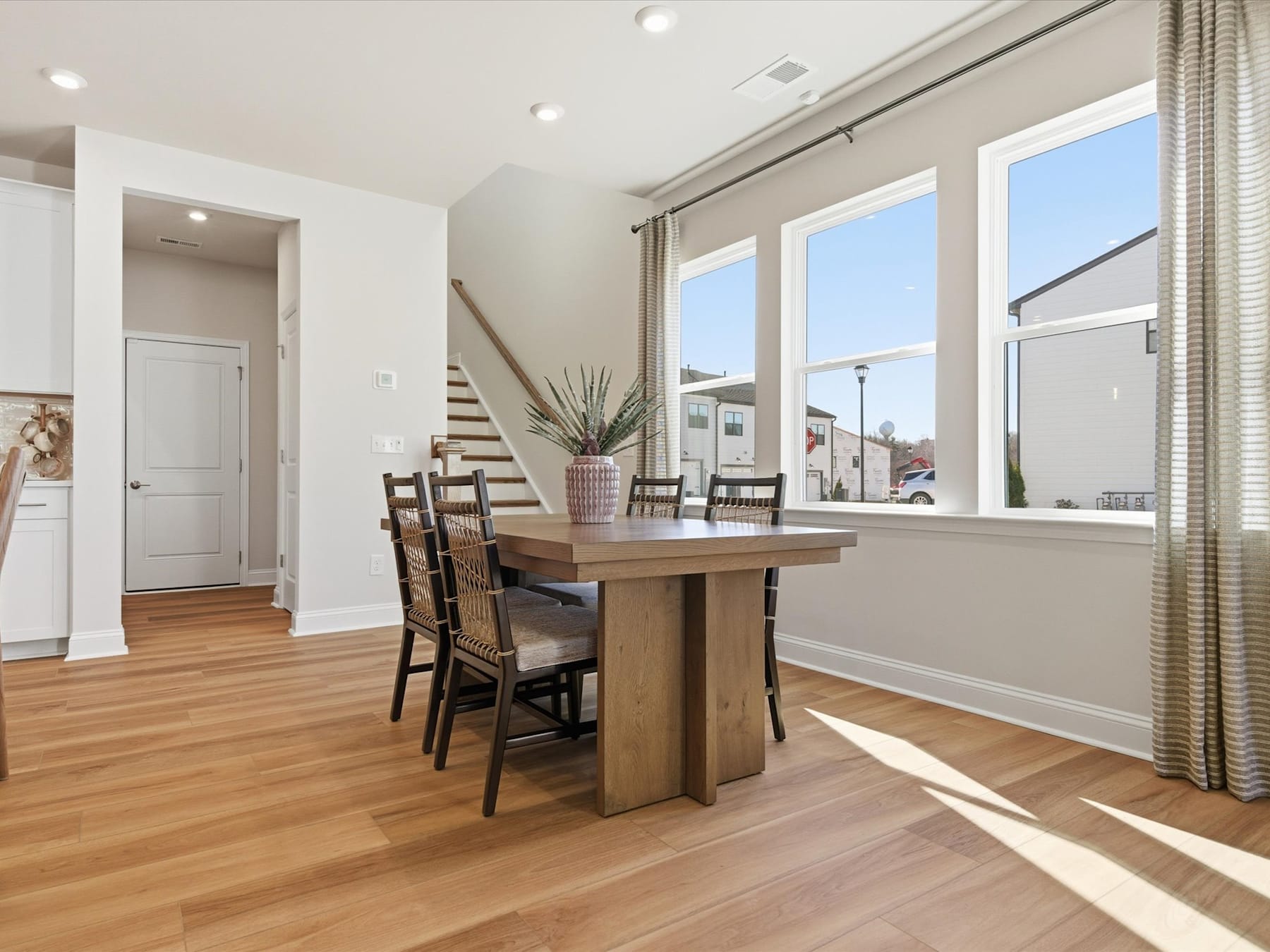 A spacious and well-lit dining area with a wooden table and chairs, surrounded by large windows that let in natural light and offer a view of the exterior.