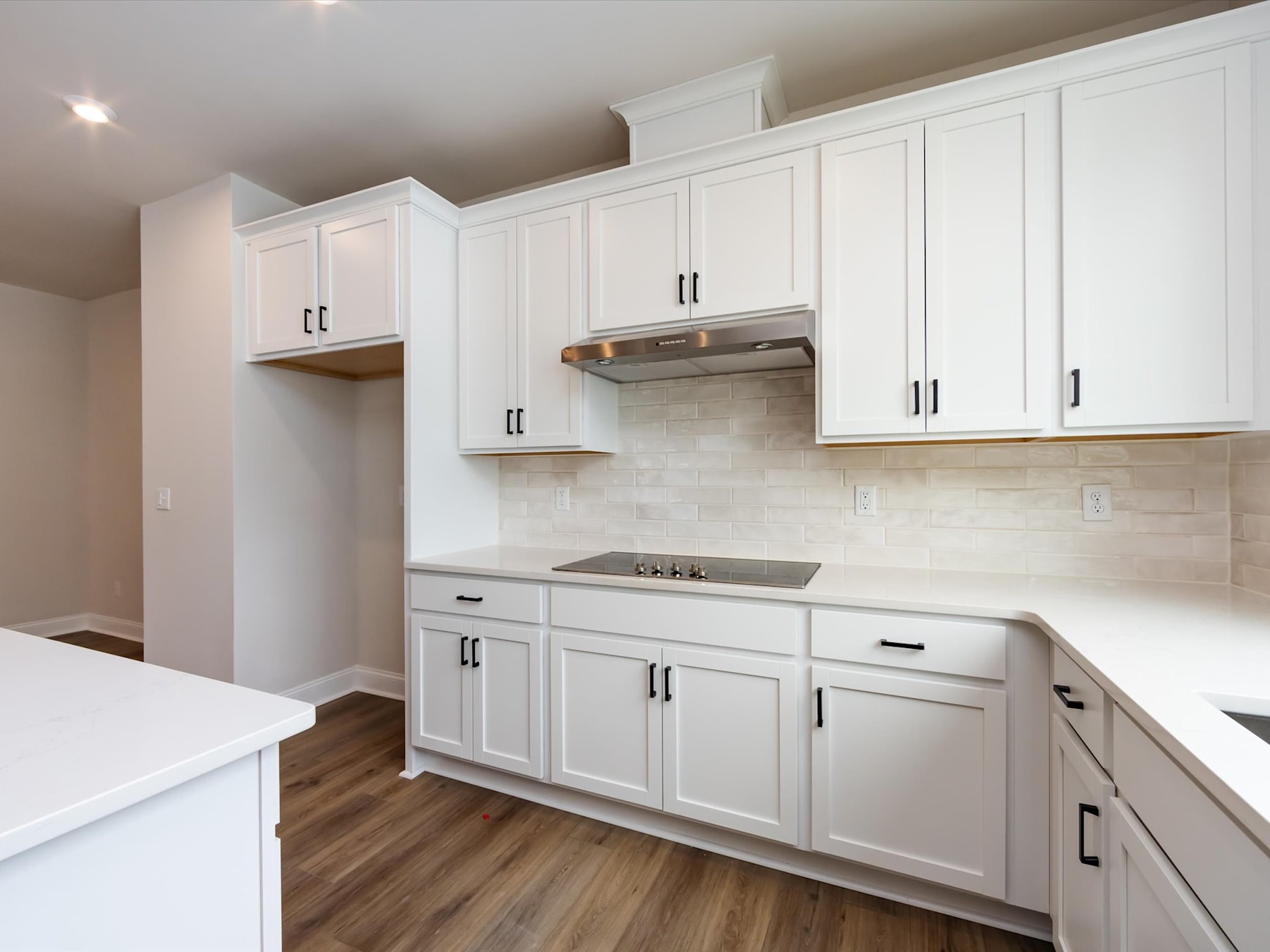 A modern, well-equipped kitchen with white cabinets, a stainless steel appliance, and a wooden floor.
