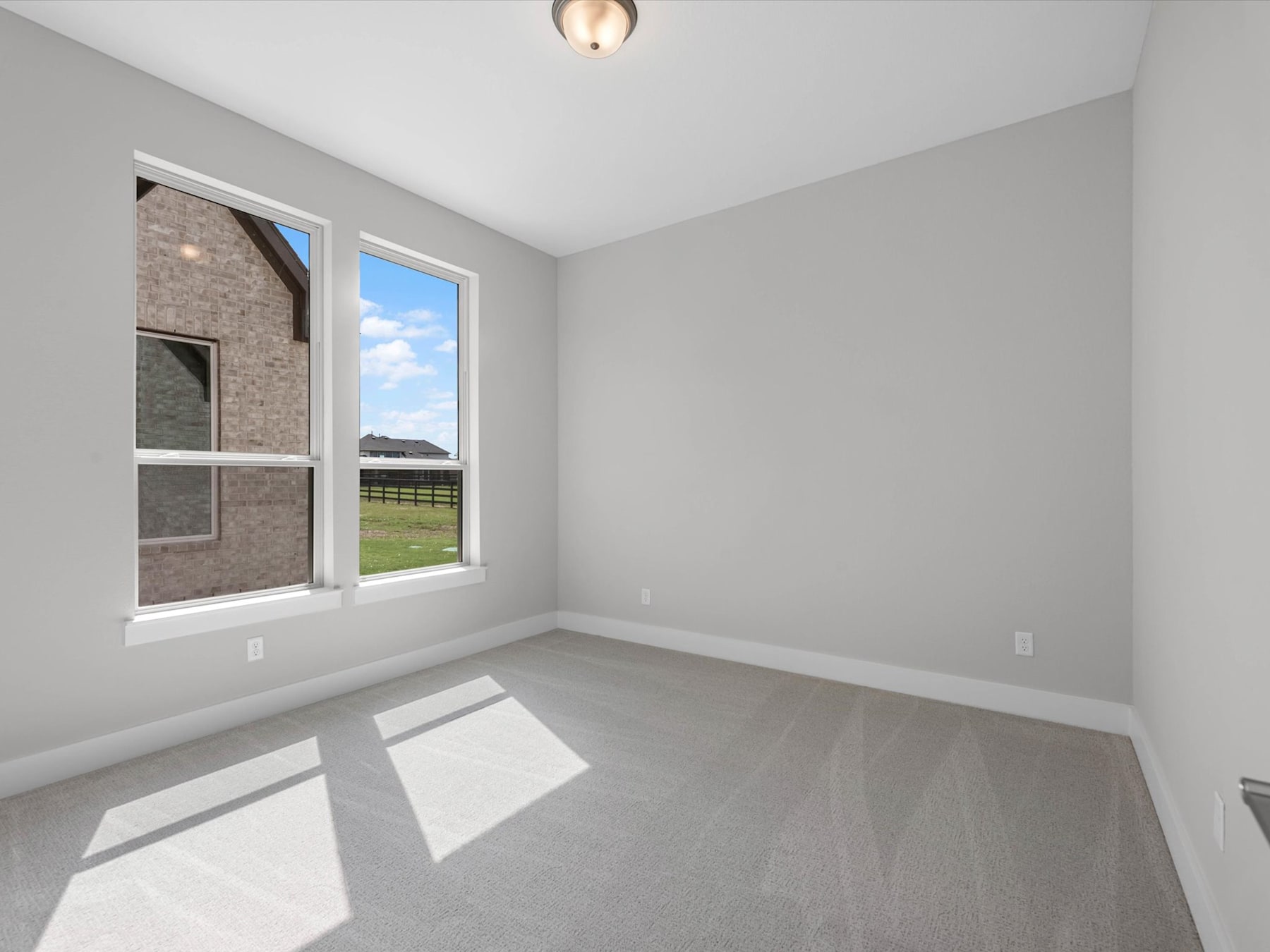 A bright and spacious room with a large window overlooking a grassy outdoor area, featuring a simple and minimalist interior design.