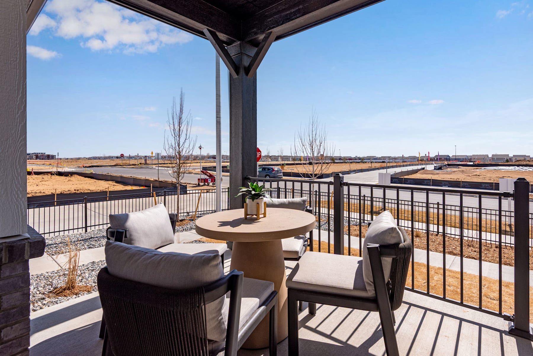 A cozy outdoor seating area with comfortable chairs and a small table, overlooking a scenic landscape with buildings and trees in the distance.
