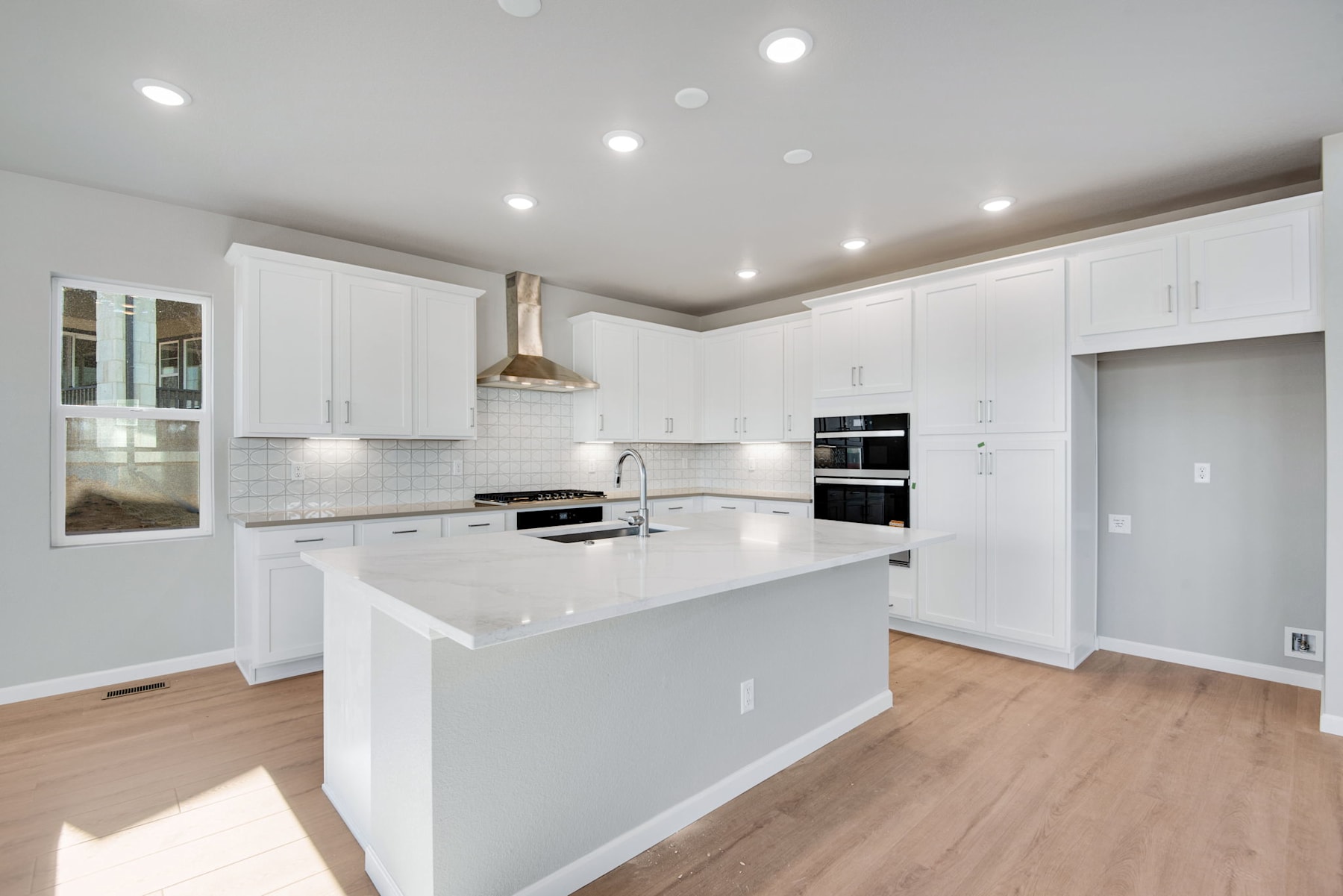 A modern, bright kitchen with white cabinets, a large island, and hardwood floors.