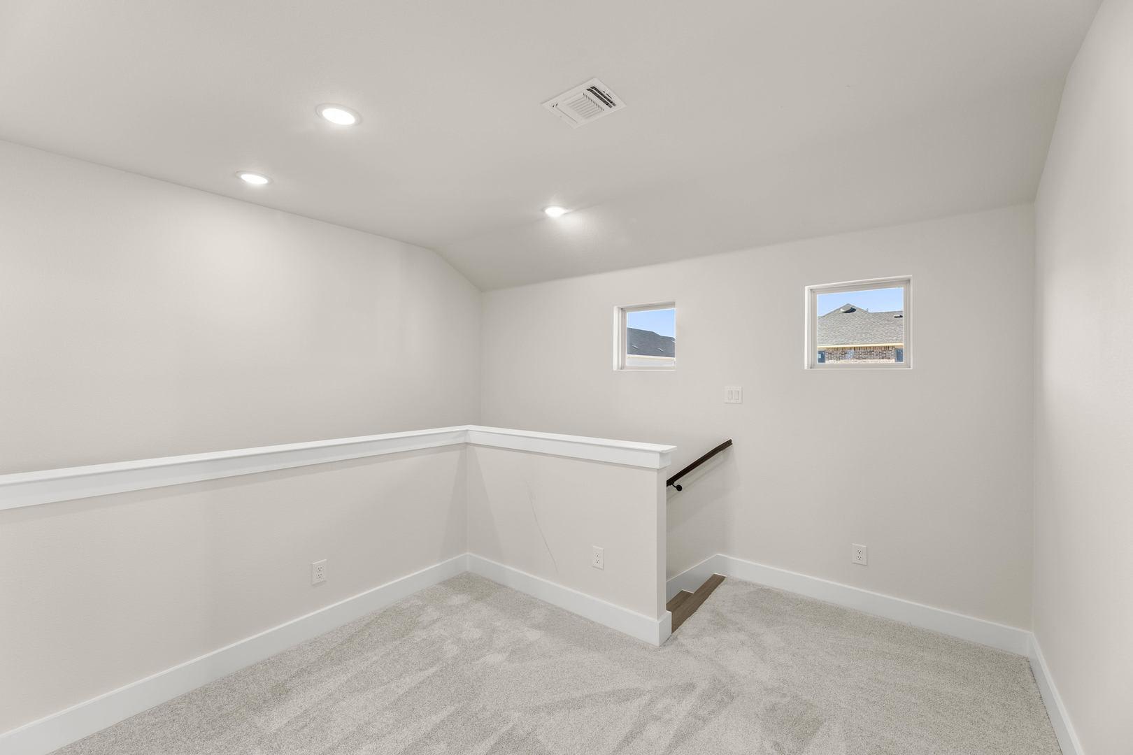 An empty, well-lit room with white walls, a tiled floor, and a staircase leading to an upper level.