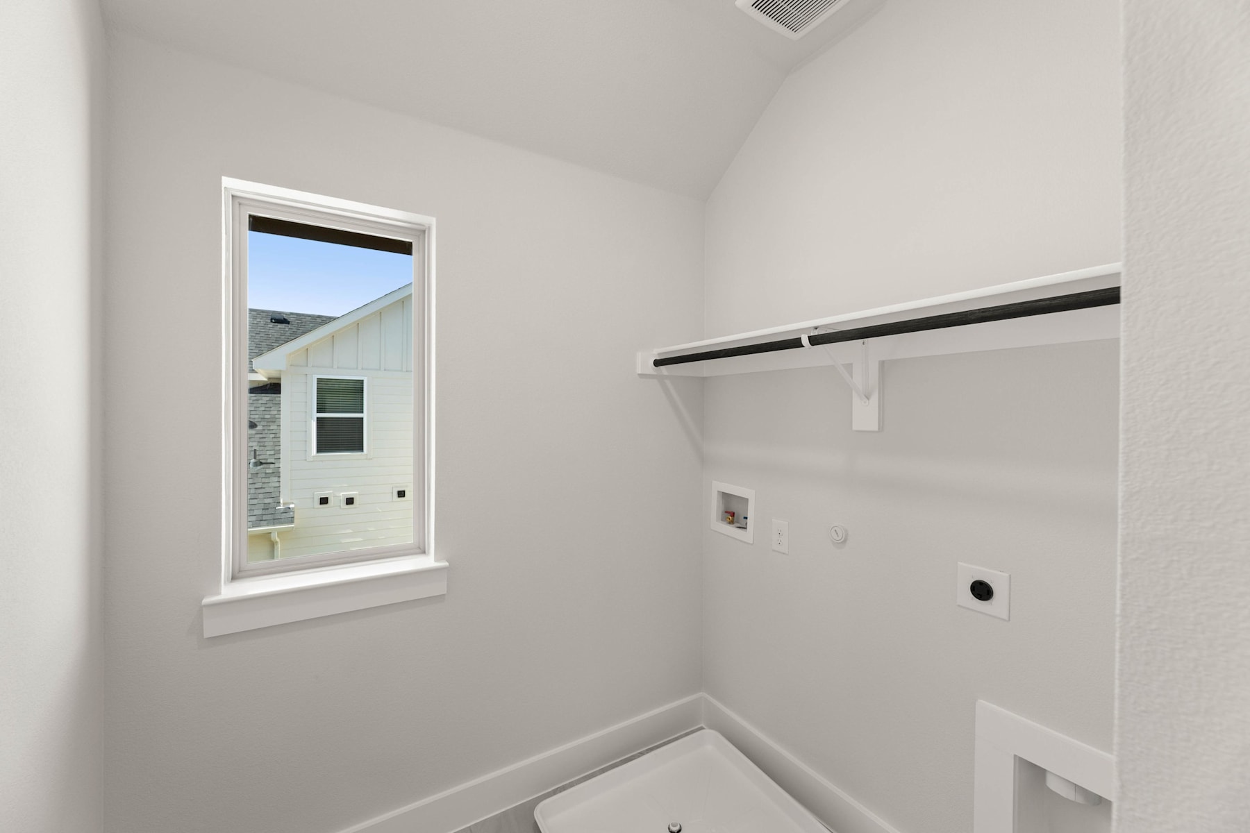 A simple, minimalist closet space with a window, a white wall, and a clothing rod for hanging items.