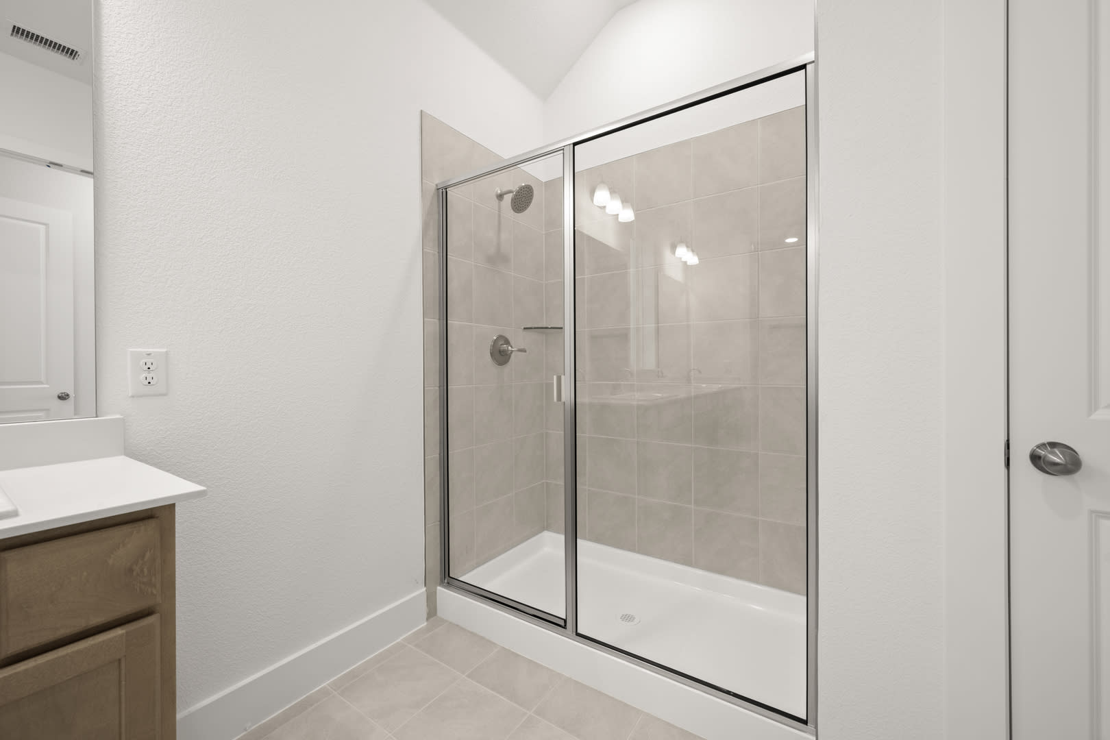 A modern, minimalist bathroom with a glass-enclosed shower, a wooden vanity, and a clean, white color scheme.