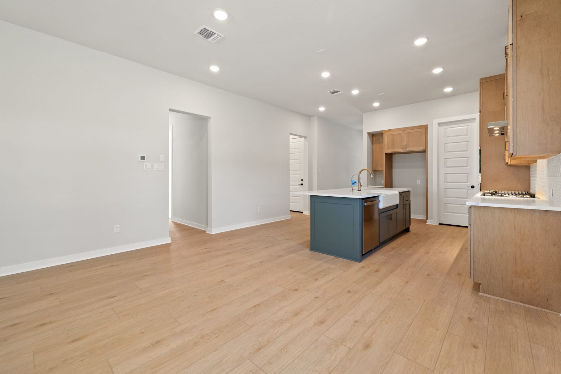 A spacious and modern open-plan living area with a kitchen island, hardwood floors, and recessed lighting.