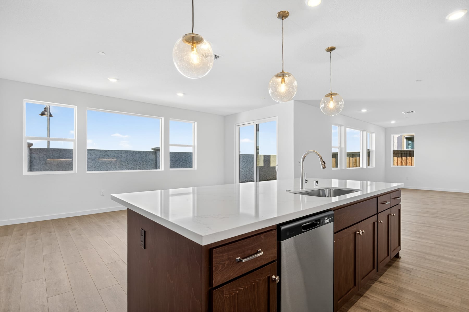 A modern, open-concept kitchen with a large island, pendant lighting, and large windows providing natural light.