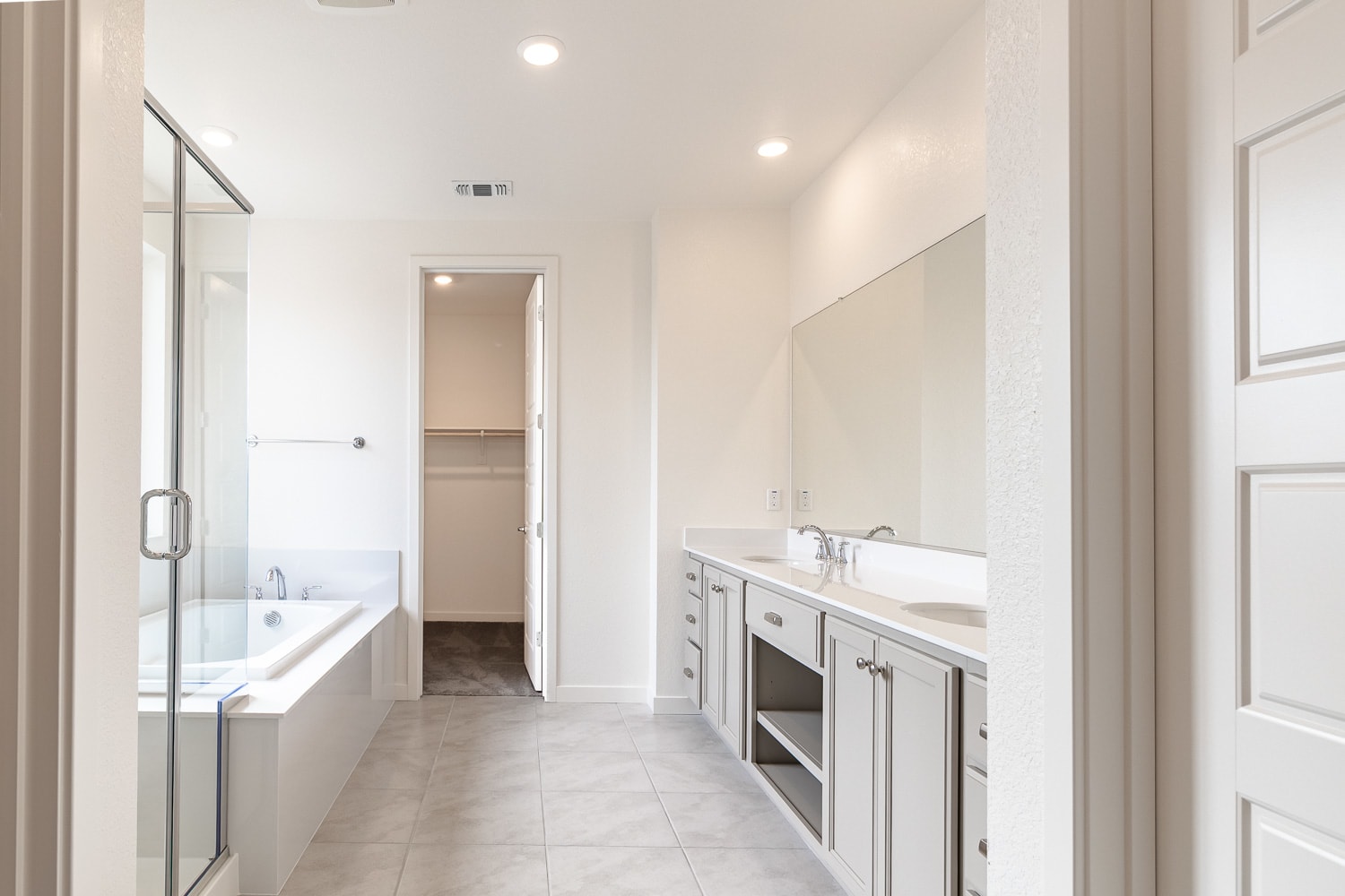 A spacious and modern bathroom with a large vanity, a bathtub, and a glass-enclosed shower area, all set against a bright and airy backdrop.