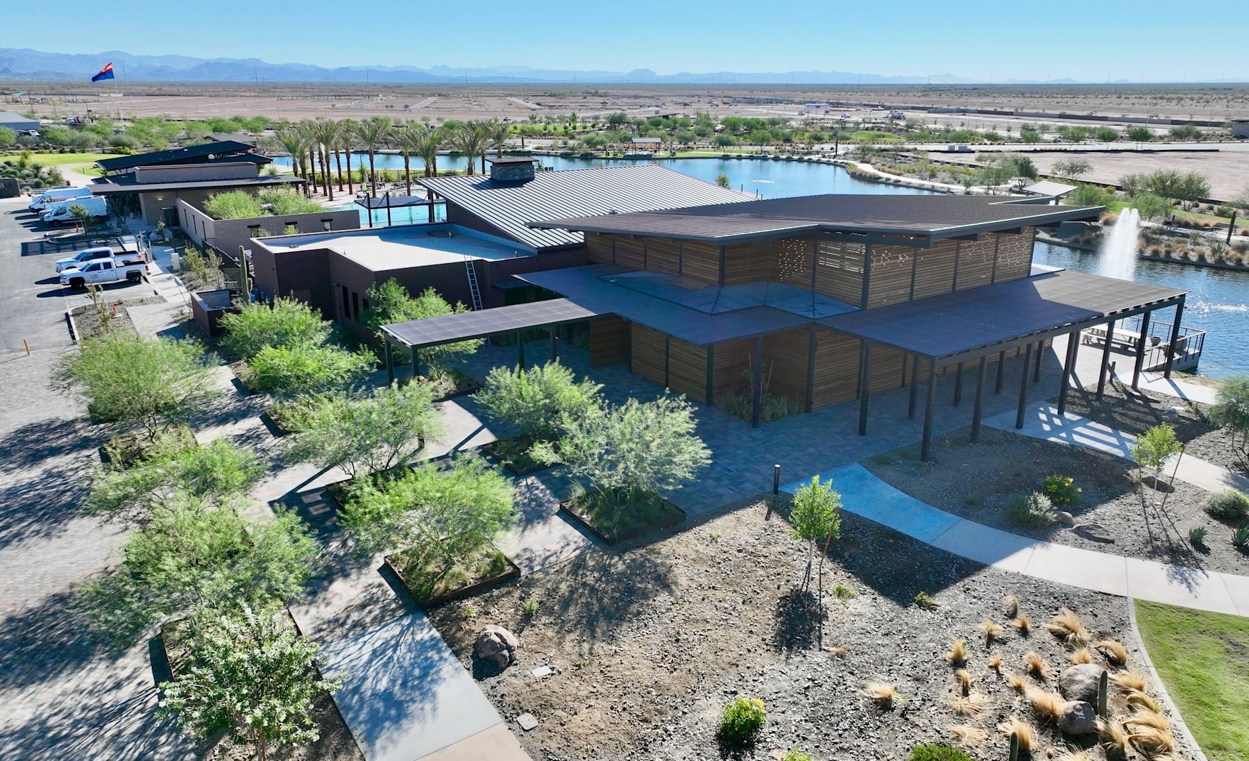 A modern, multi-level building with a distinctive architectural design sits amidst a lush, landscaped environment, overlooking a vast expanse of desert terrain and distant mountains.