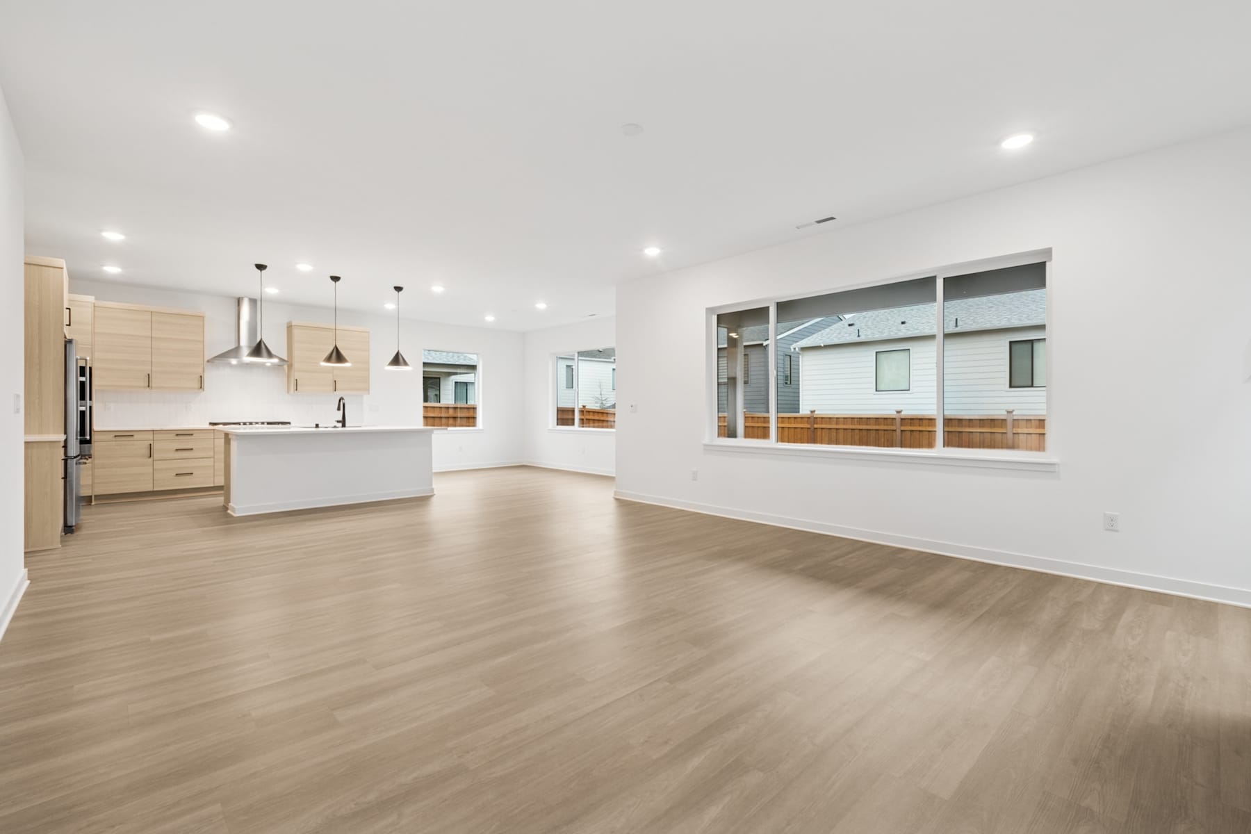 A spacious, open-concept living area with a modern kitchen, hardwood floors, and large windows providing ample natural light.