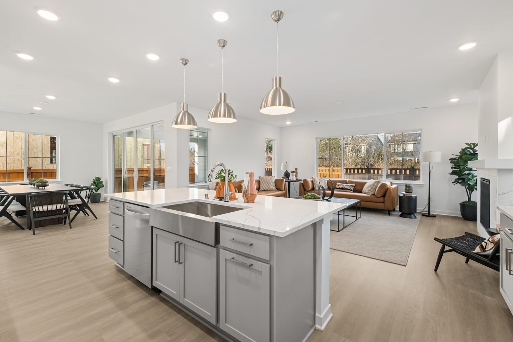 A modern and spacious open-concept kitchen and living room with a central island, pendant lighting, and a mix of natural and industrial design elements.