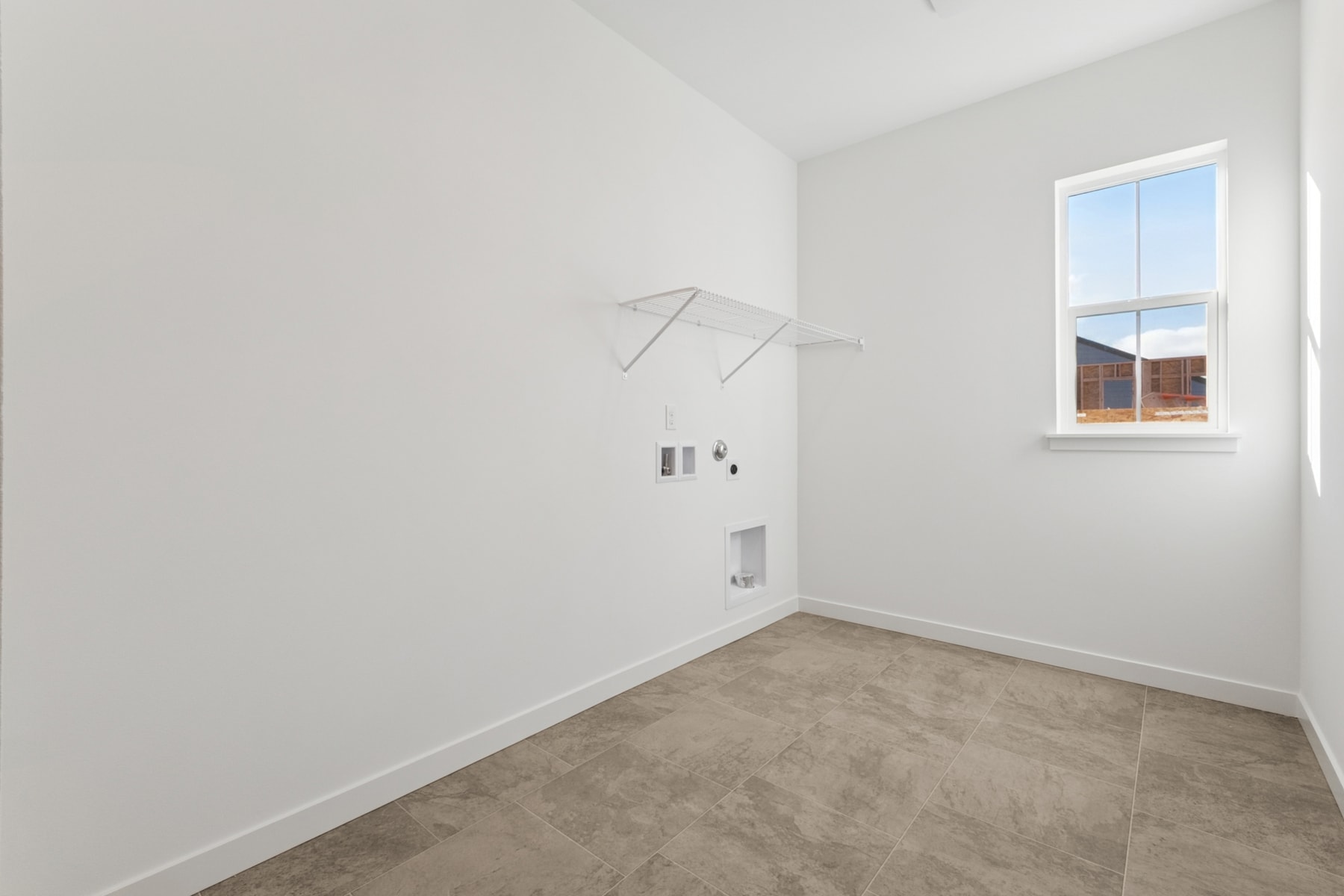 A bright, empty room with white walls, a window, and a clothes rack on the wall.