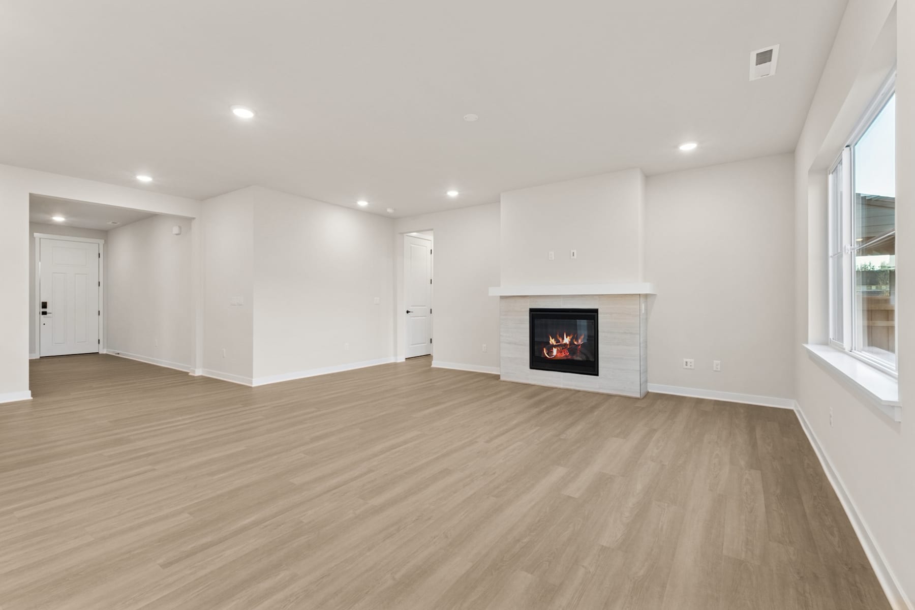 A spacious, well-lit room with a fireplace and hardwood flooring, creating a warm and inviting atmosphere.