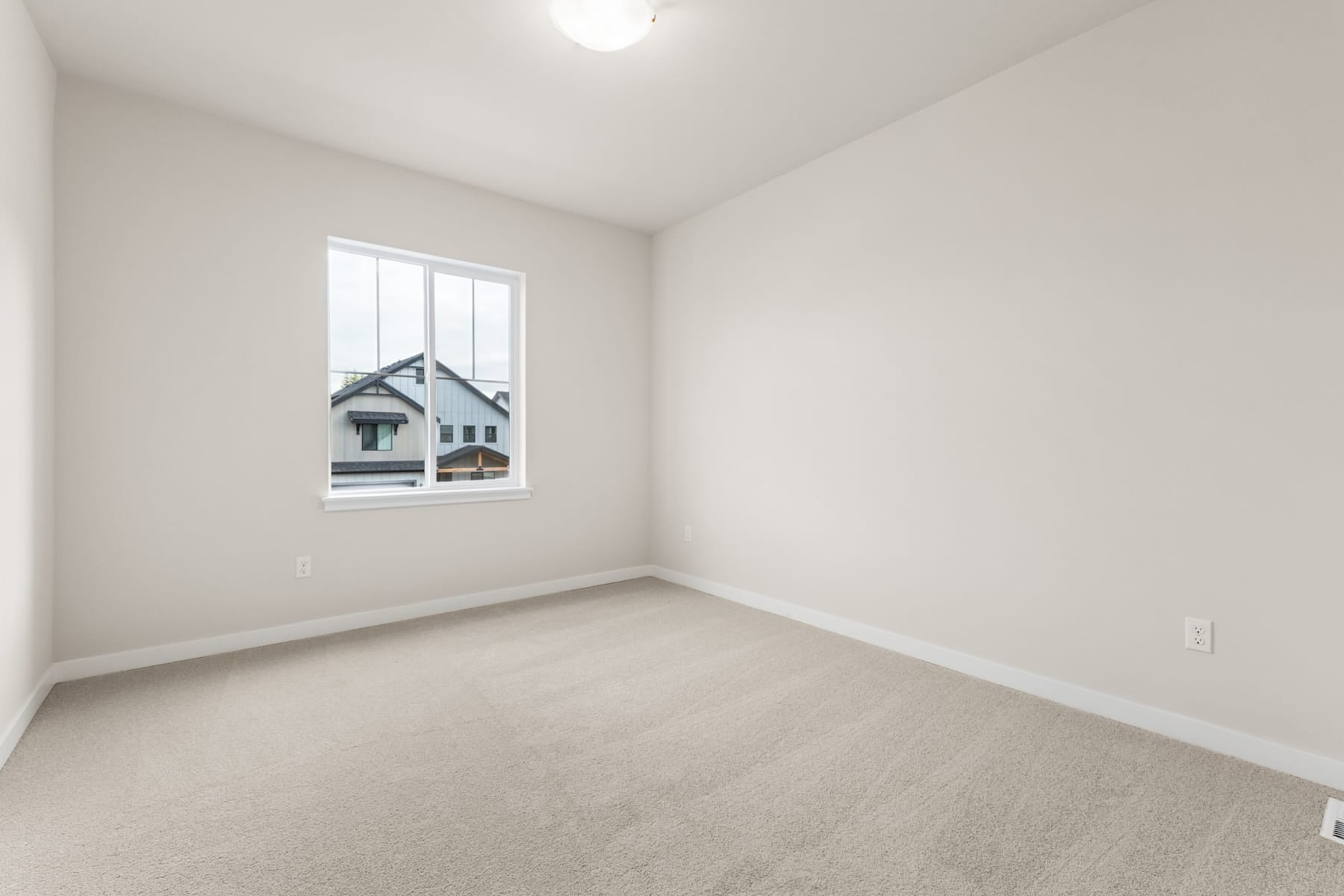A simple, minimalist bedroom with a large window overlooking a snowy landscape outside.
