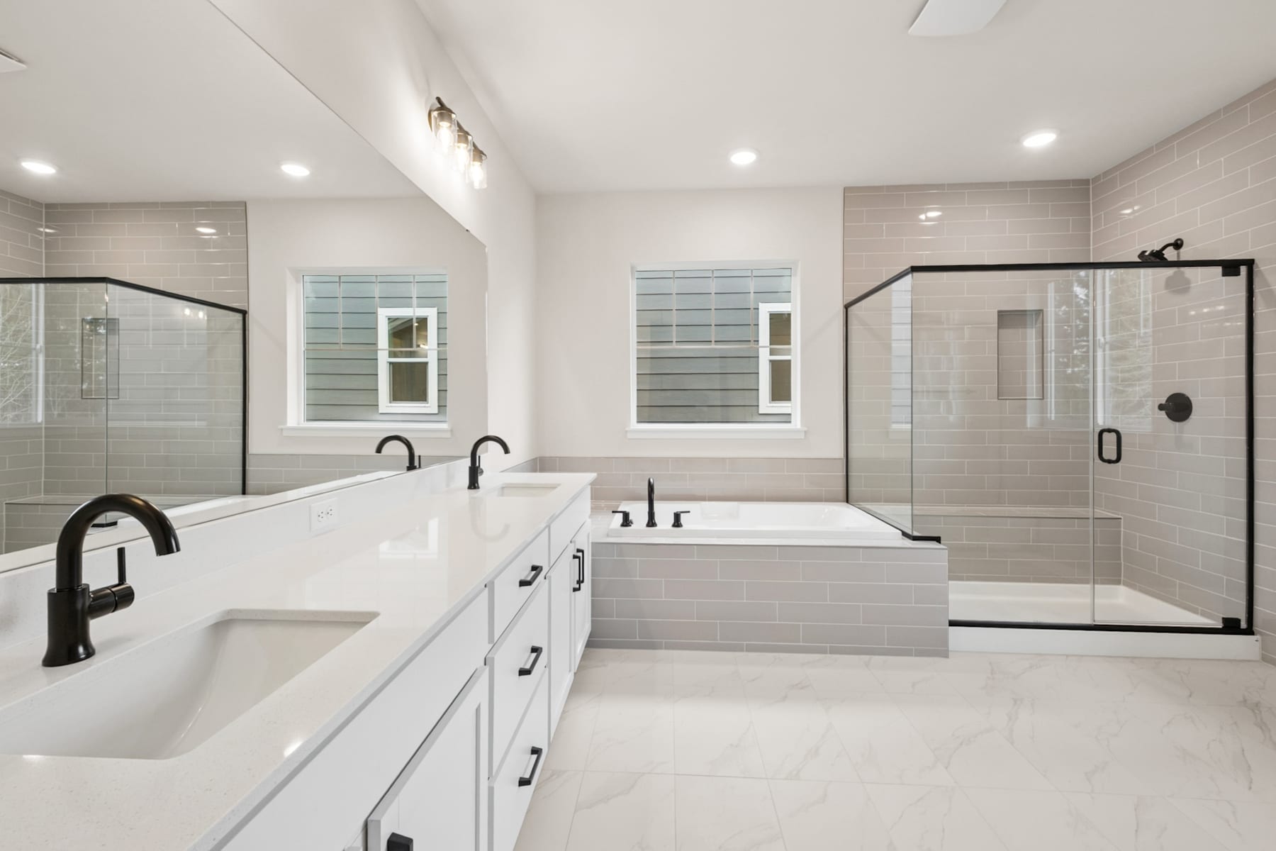 A modern, spacious bathroom with white cabinets, a freestanding bathtub, and glass-enclosed showers, all set against a neutral color palette.