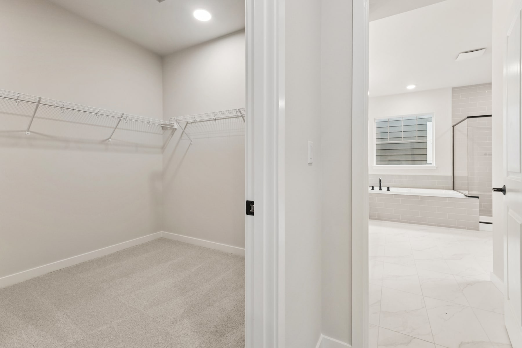 A bright, minimalist room with a closet and a bathroom visible through an open doorway.