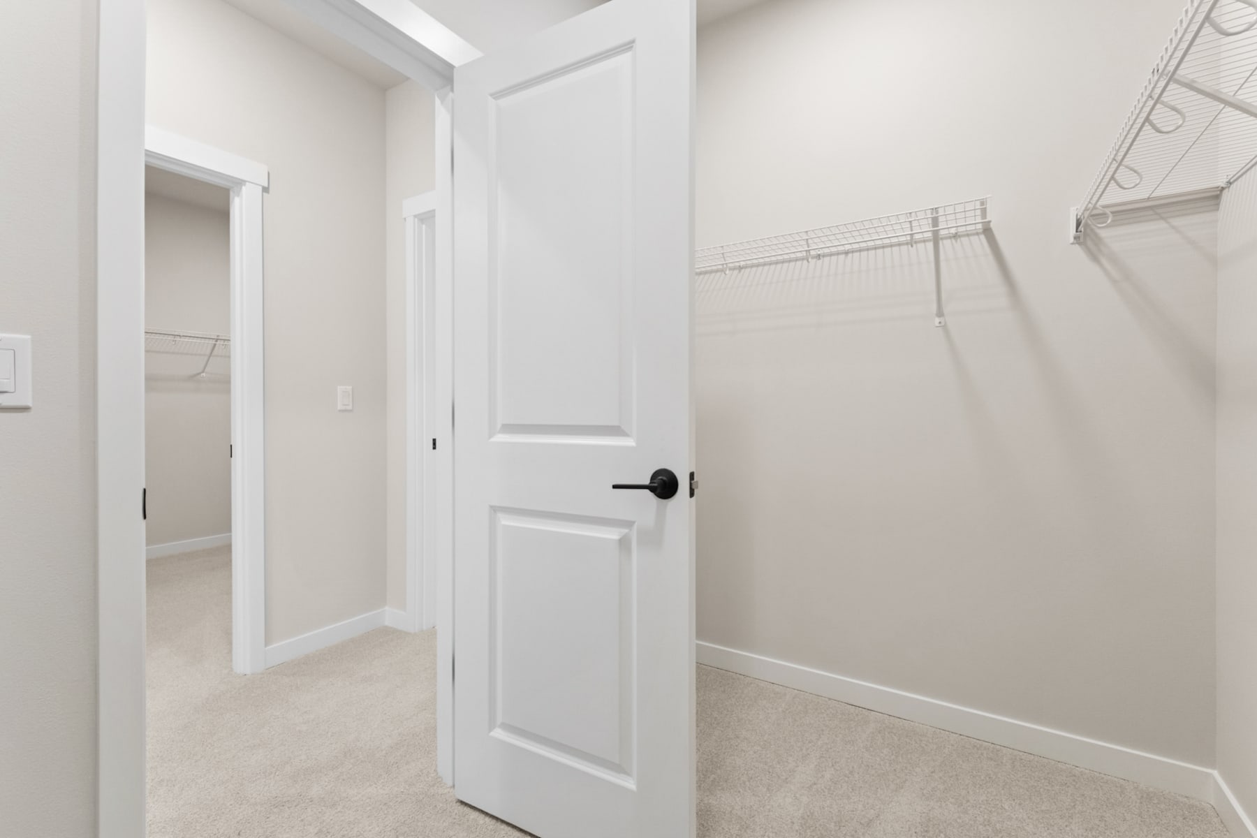 A bright, minimalist hallway with a white door and a closet space visible in the background.