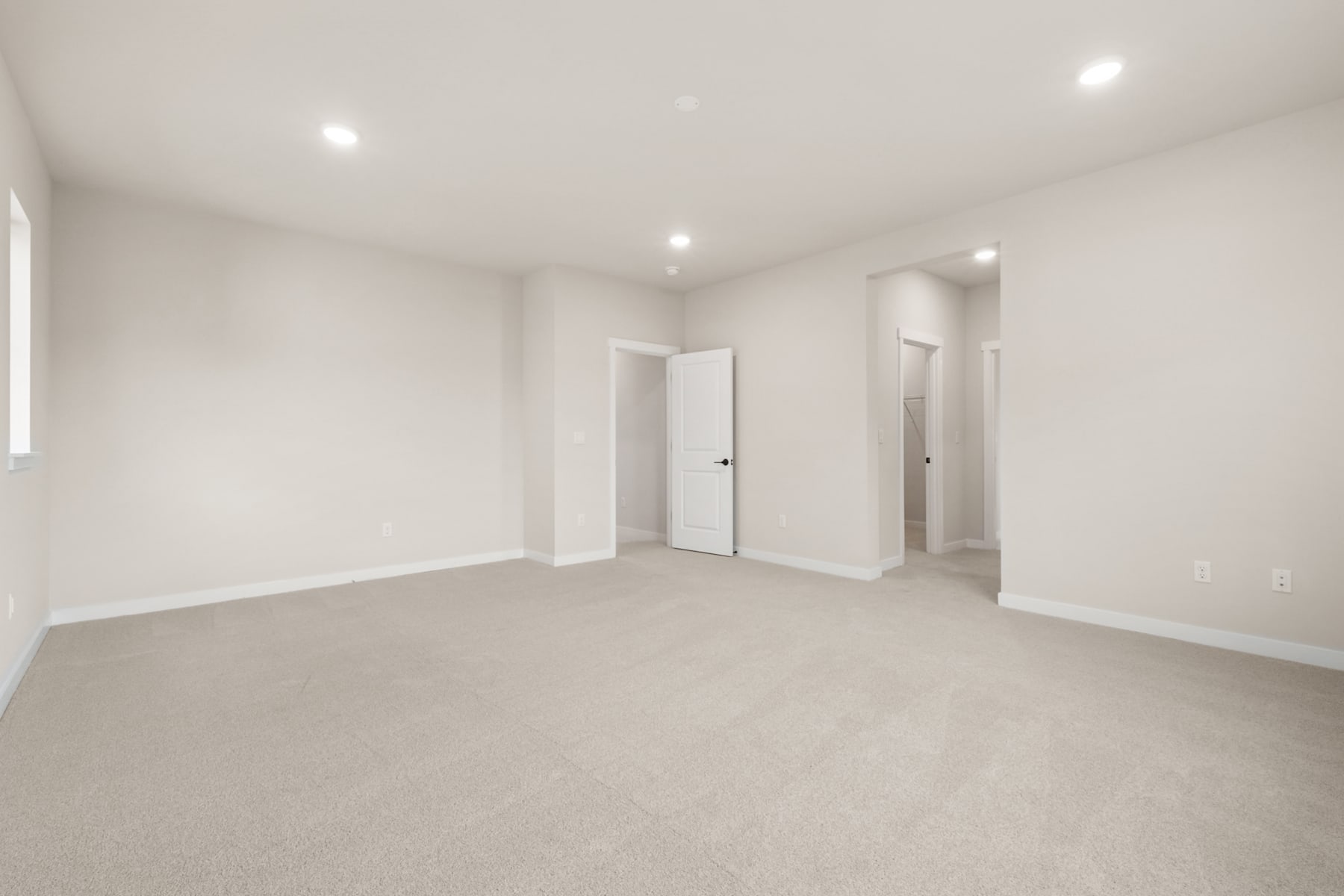 A spacious, minimalist room with white walls, recessed lighting, and a carpeted floor, creating a clean and bright atmosphere.