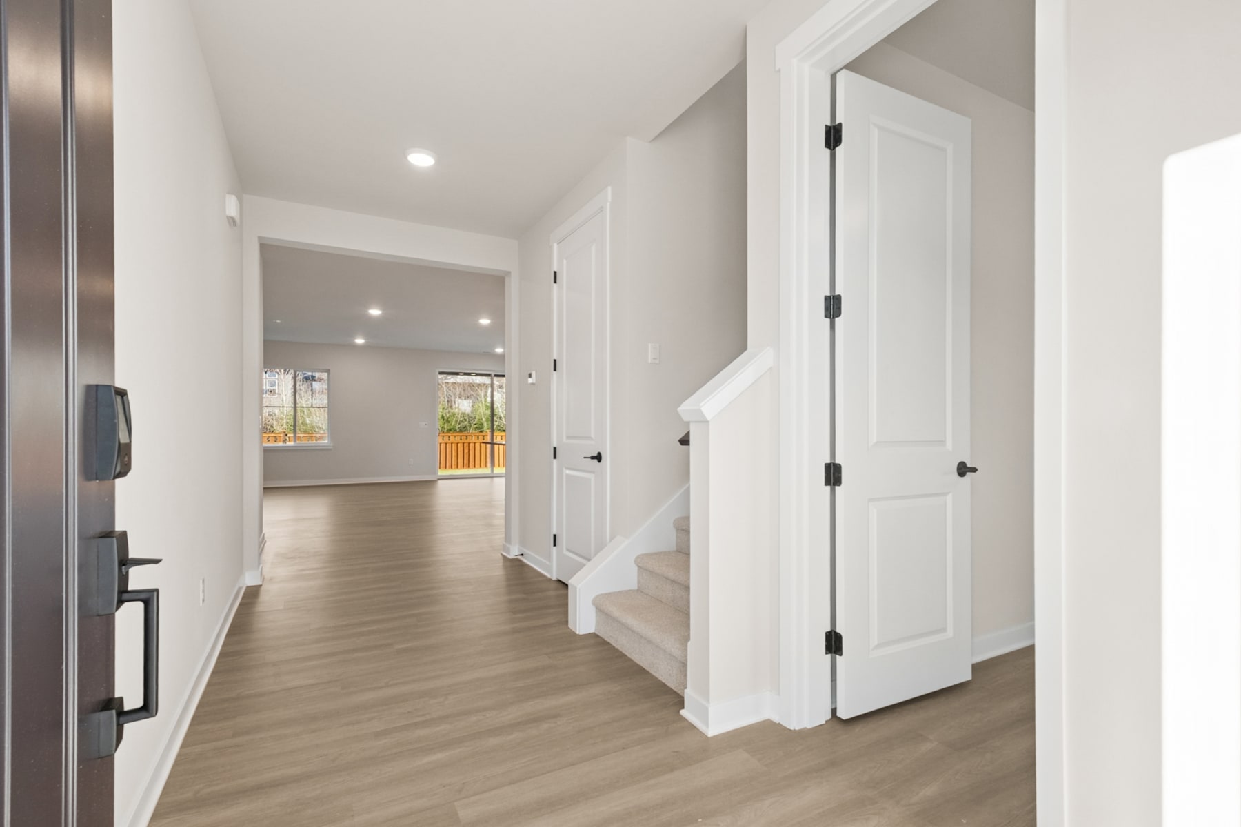 A bright and spacious hallway with white walls, wooden floors, and several doors leading to other rooms.