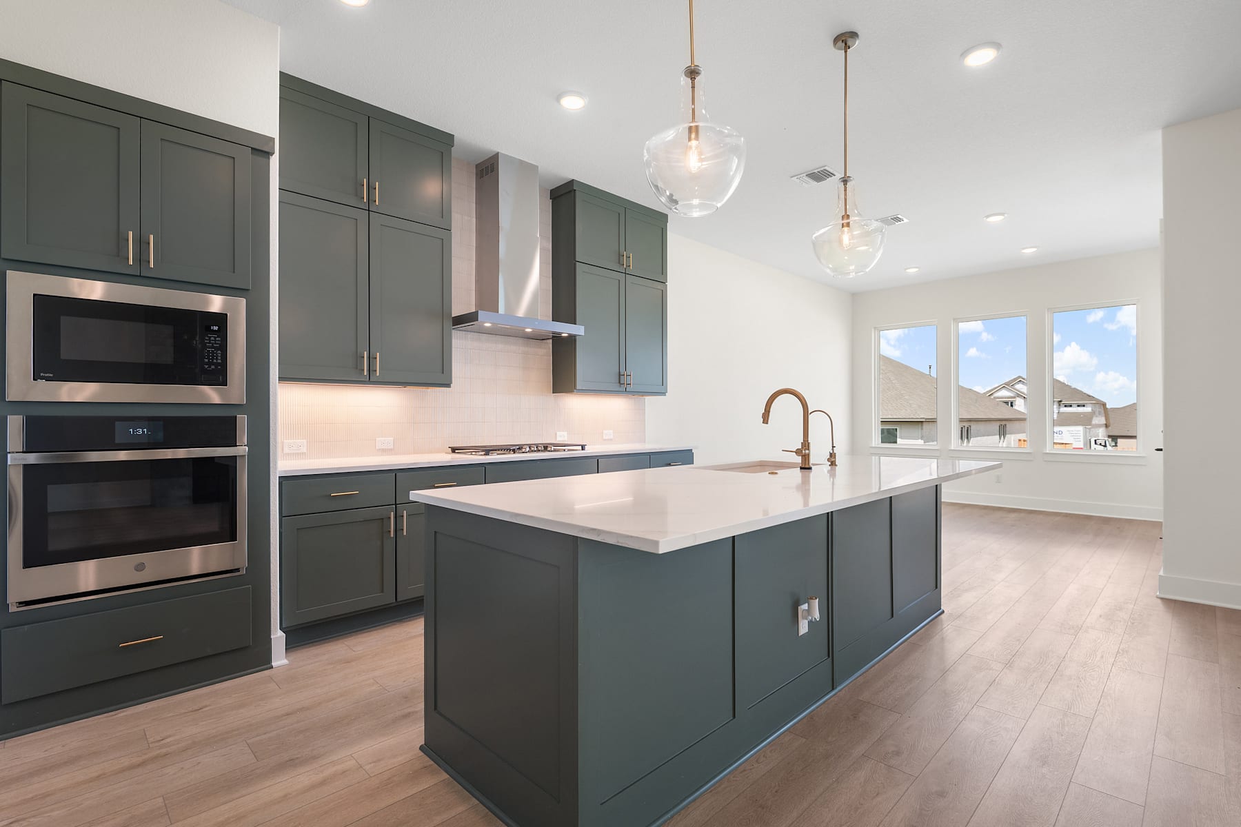 A modern, well-designed kitchen with dark gray cabinets, stainless steel appliances, and a central island with a white countertop, set against a bright and airy background.