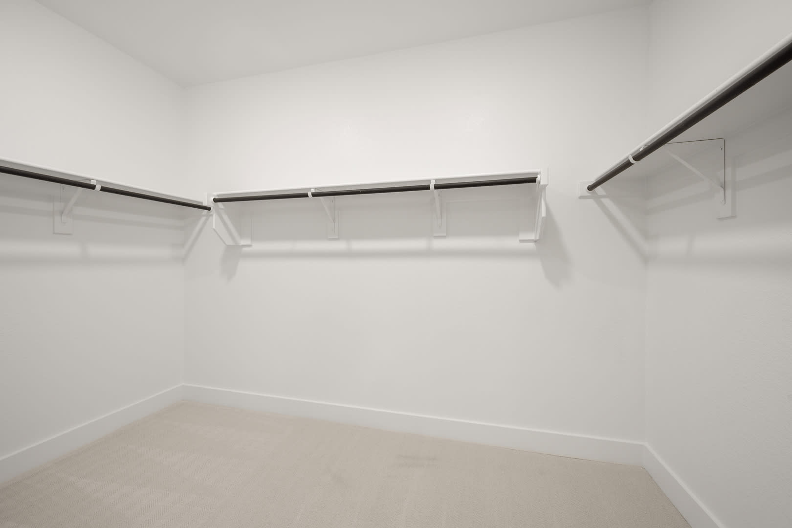 A minimalist, white-walled closet space with metal clothing rods and shelves, creating a clean and organized storage area.