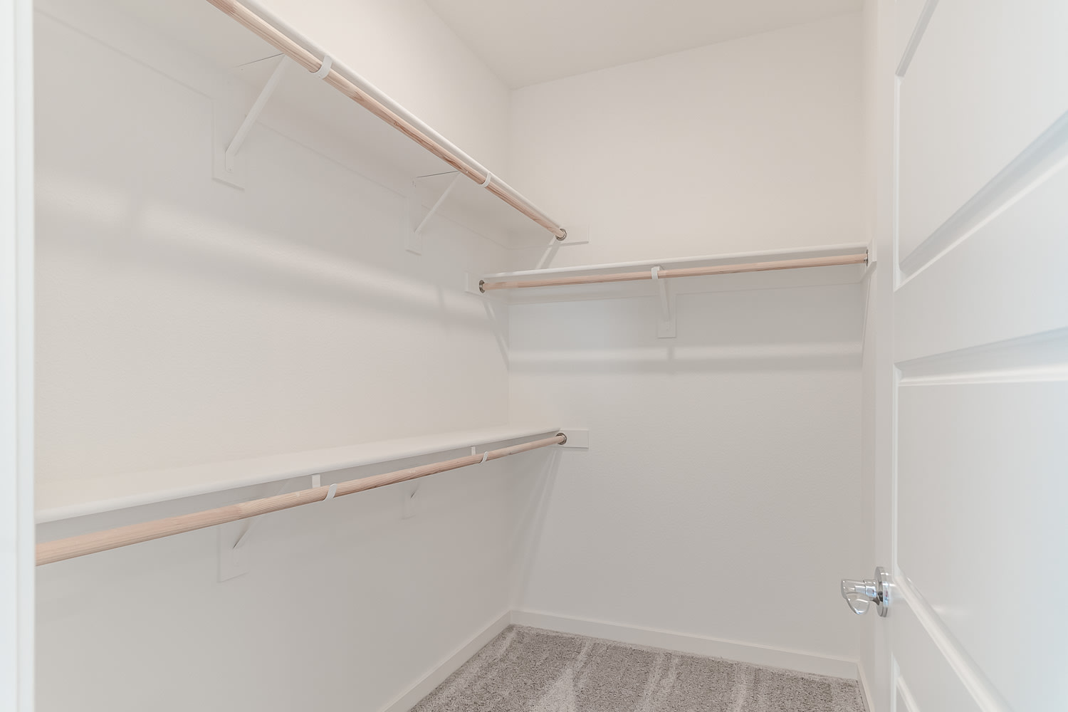 A simple, minimalist closet space with white walls and wooden shelving units.
