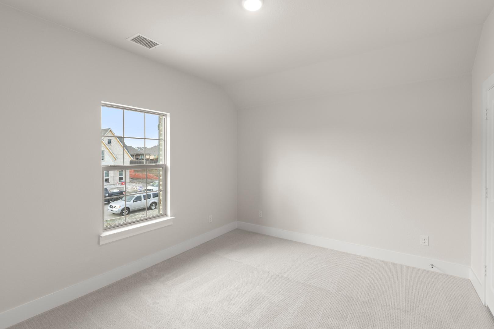 A bright, empty room with a large window overlooking a street scene in the background.