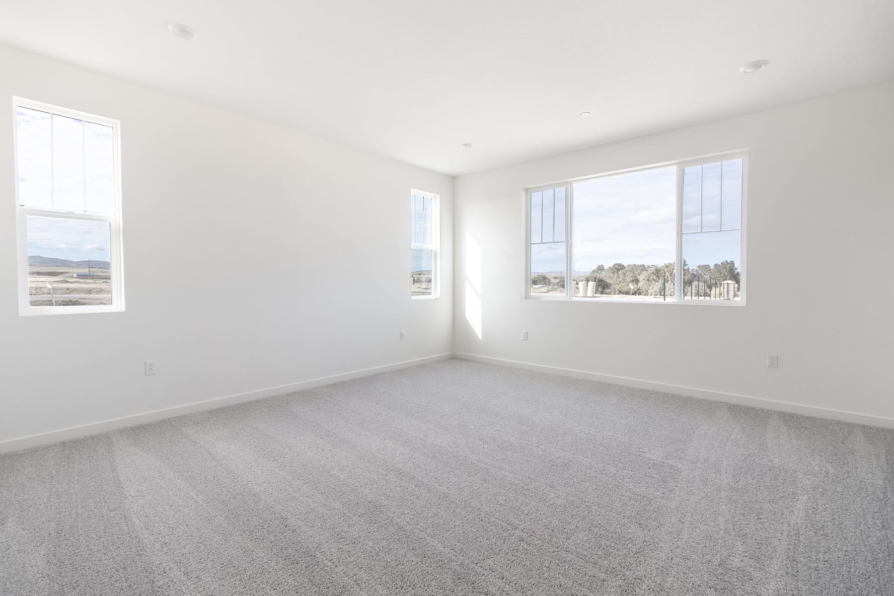 A bright, empty room with large windows overlooking a scenic outdoor landscape.