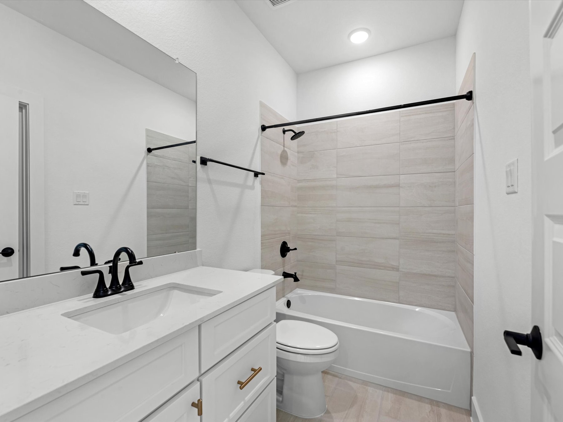 A modern, minimalist bathroom with a white vanity, a large mirror, and a tiled shower enclosure.
