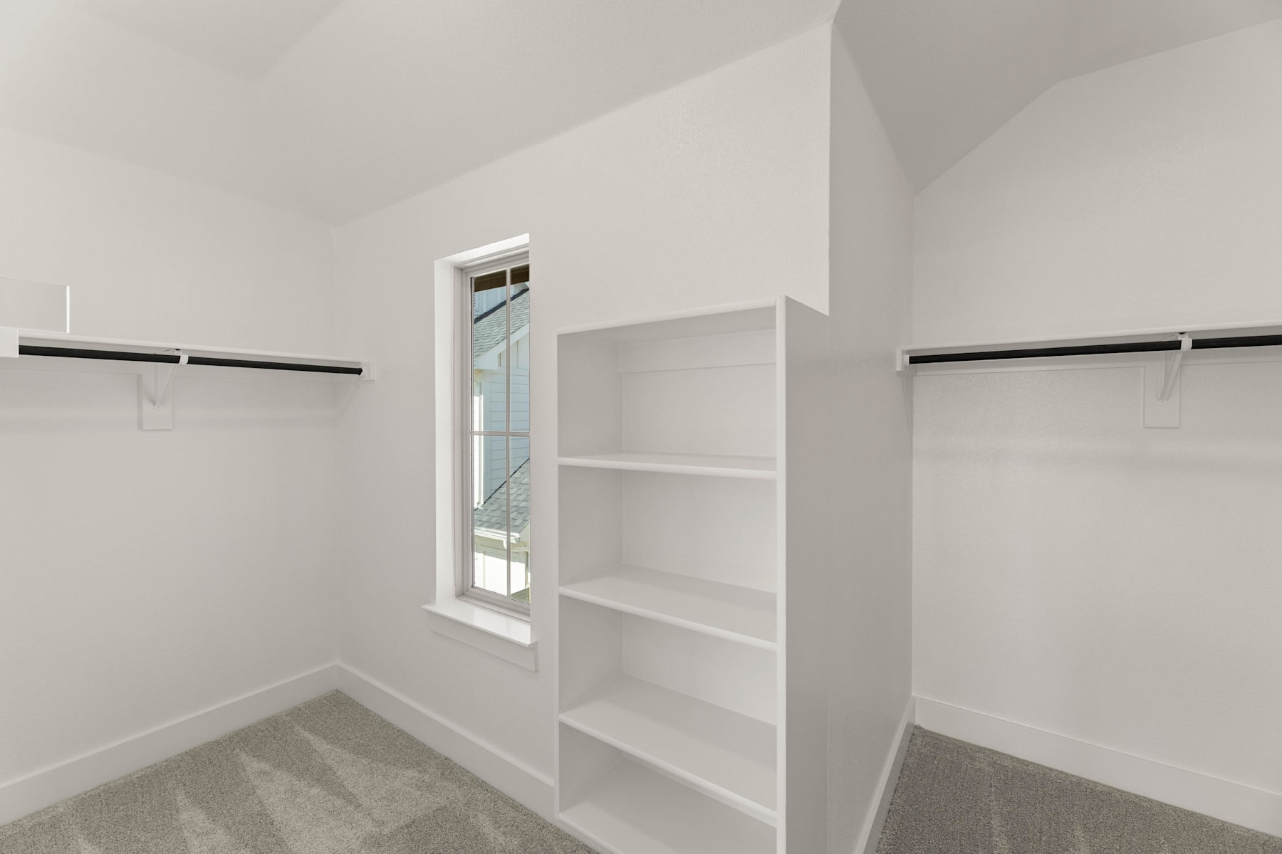 A minimalist, well-lit room with a white shelving unit and clothing rods against the walls, creating a clean and organized closet space.