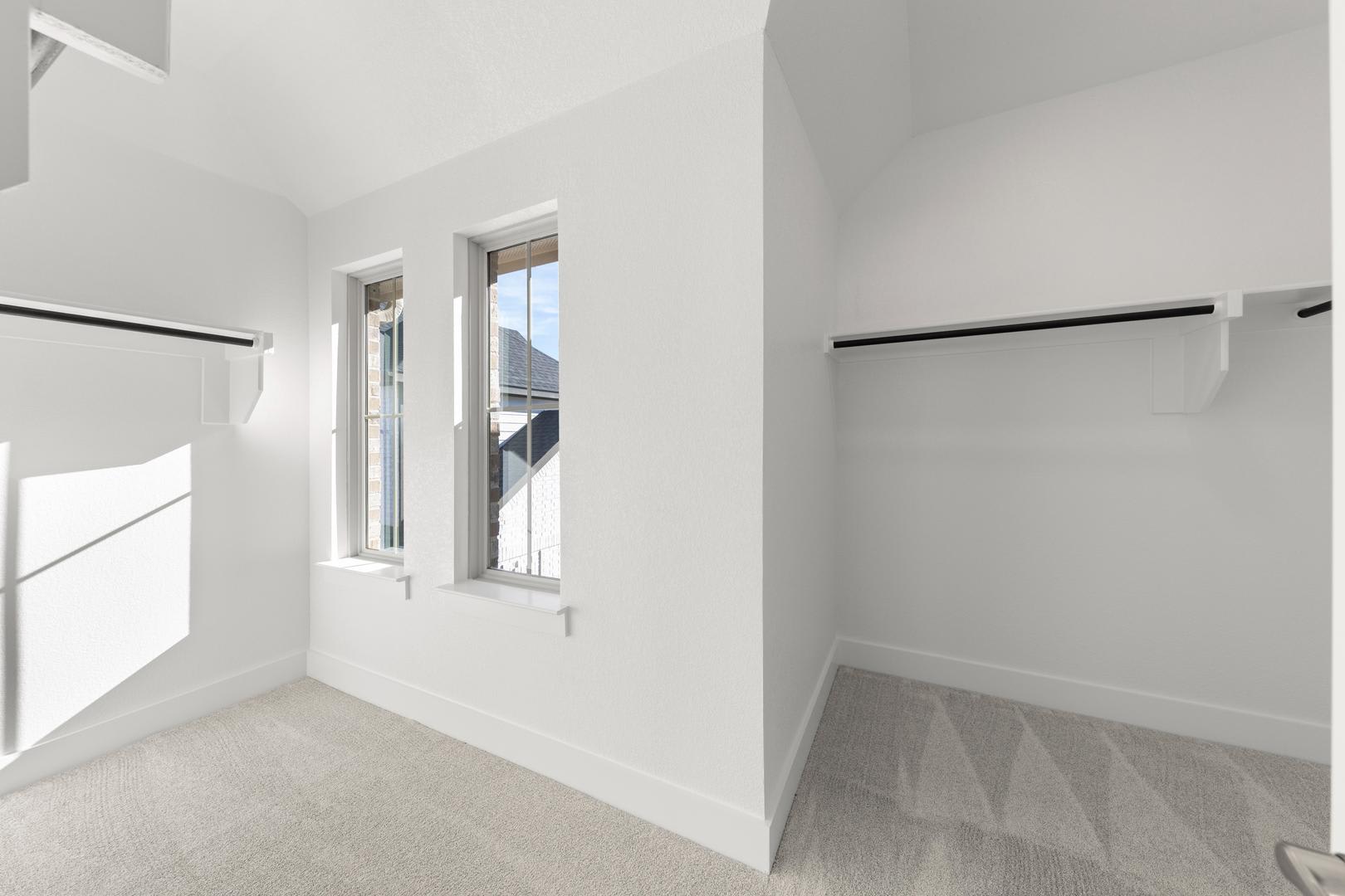 A bright, minimalist room with white walls, a window, and a closet with hanging rods.