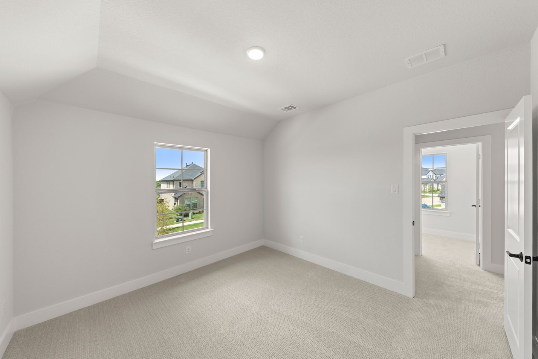 A bright, empty room with white walls, a window, and a door leading to the exterior of the building.