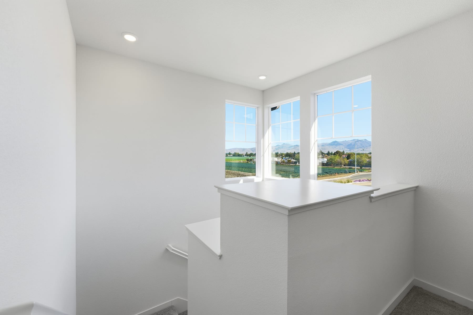 A bright and airy interior space with large windows overlooking a scenic outdoor landscape in the background.