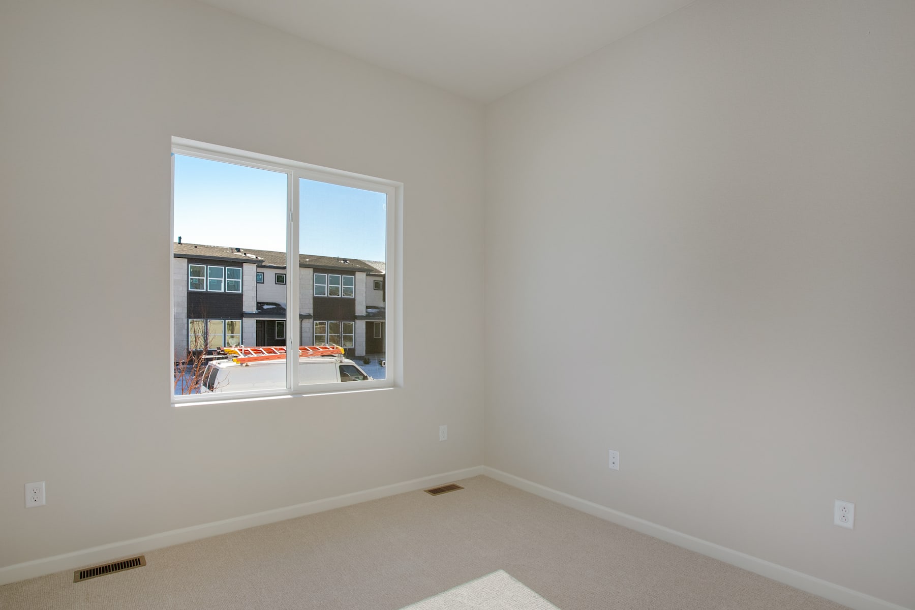 A bright and airy room with a large window overlooking a residential area in the background.