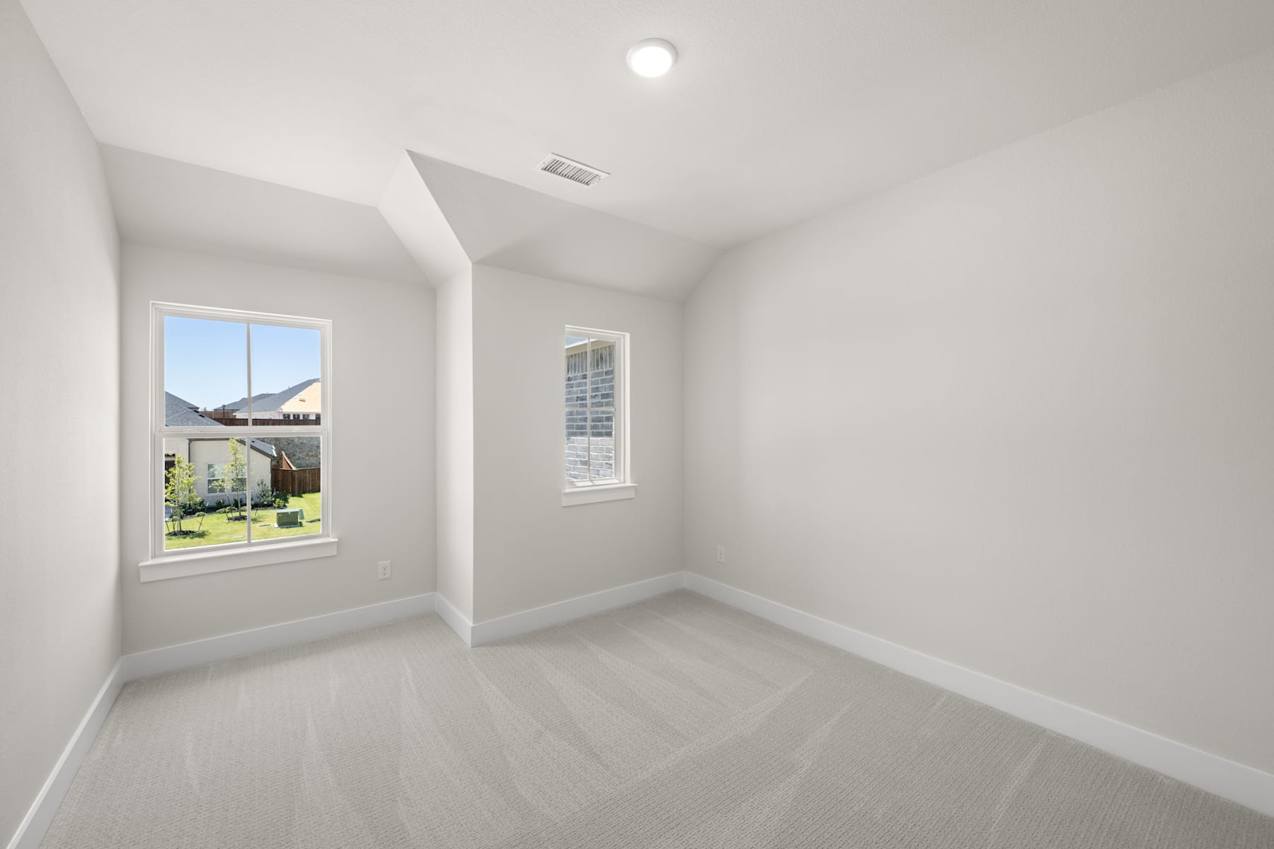 A bright, empty room with a window overlooking a grassy outdoor area.