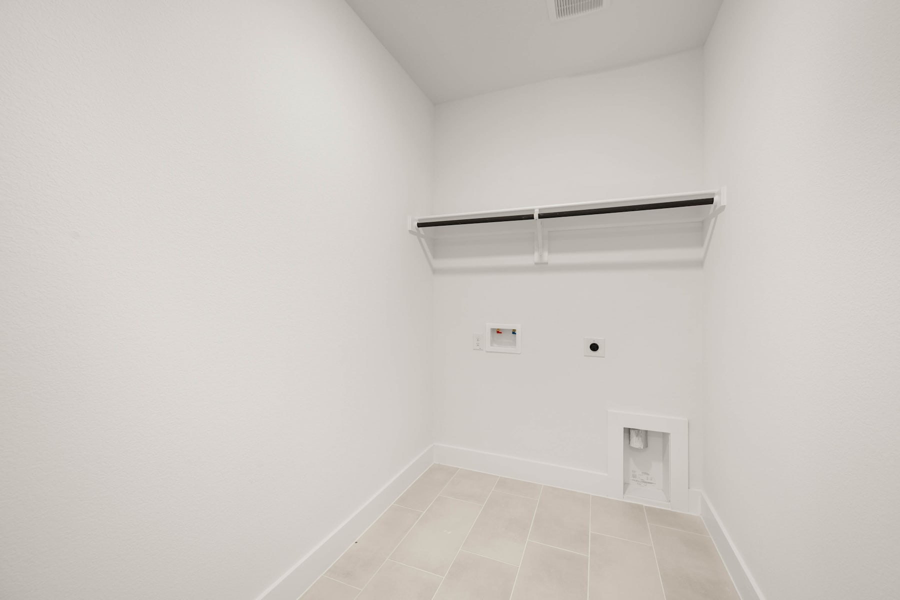 A simple, minimalist room with white walls, a light-colored floor, and a closet rod mounted on the wall.