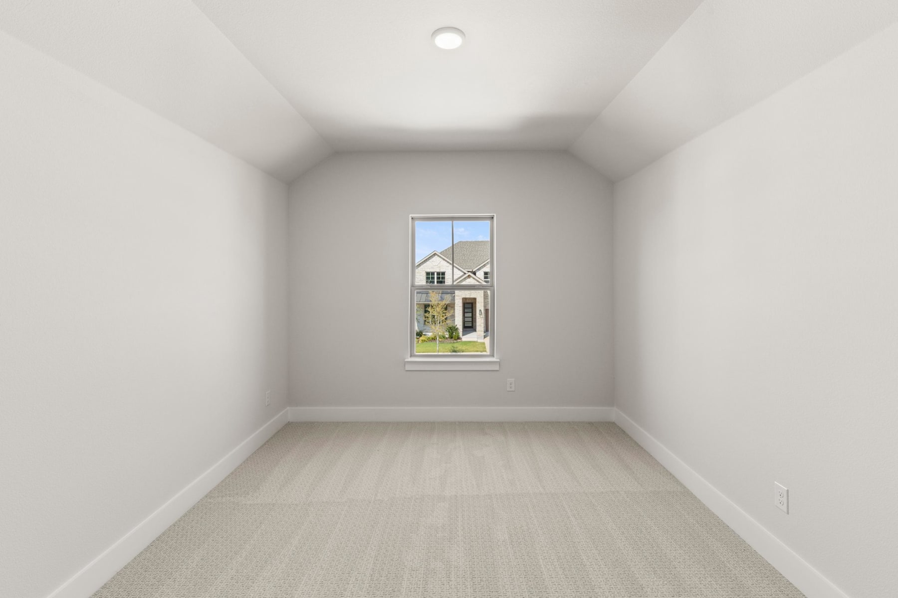 A simple, minimalist room with a window framing a view of a house in the background, creating a sense of openness and natural light.