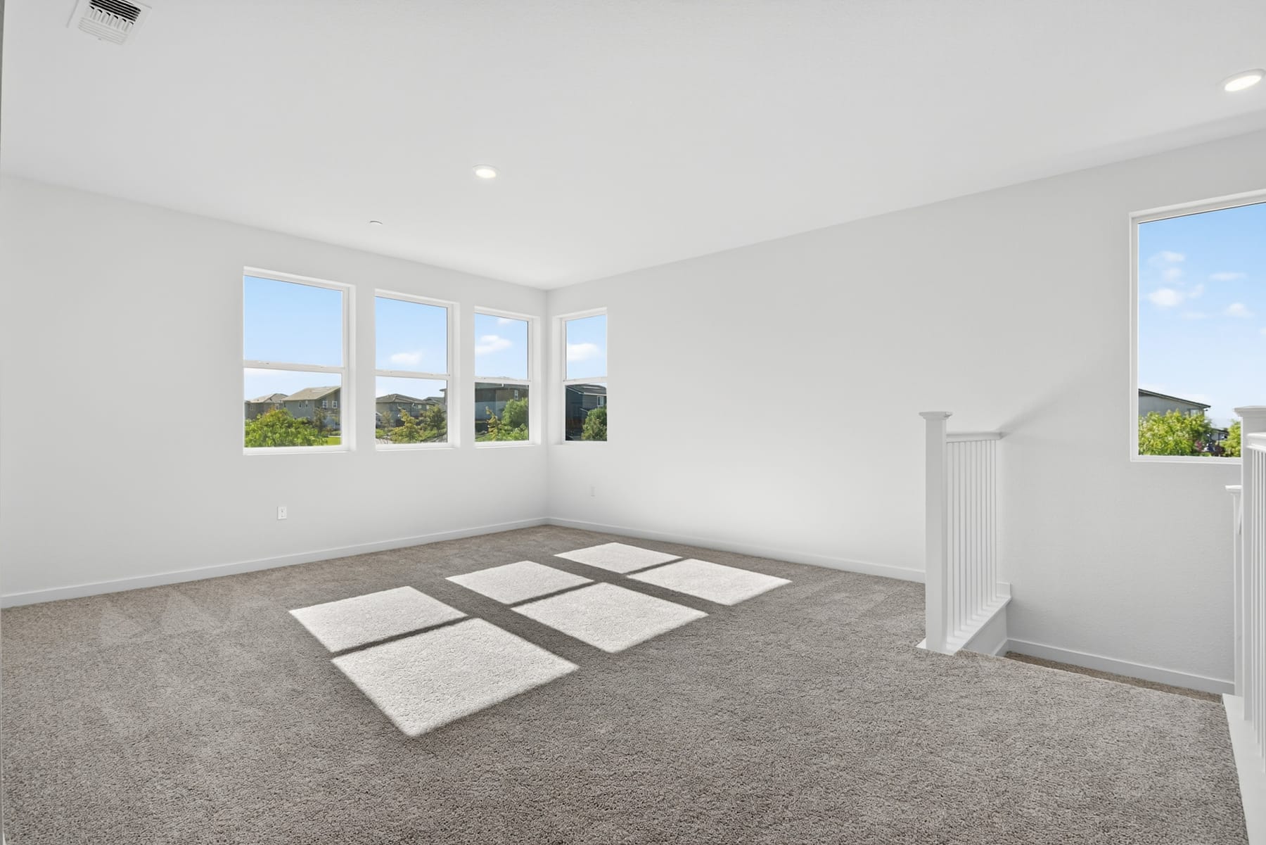 An empty, bright room with large windows overlooking a scenic outdoor landscape.