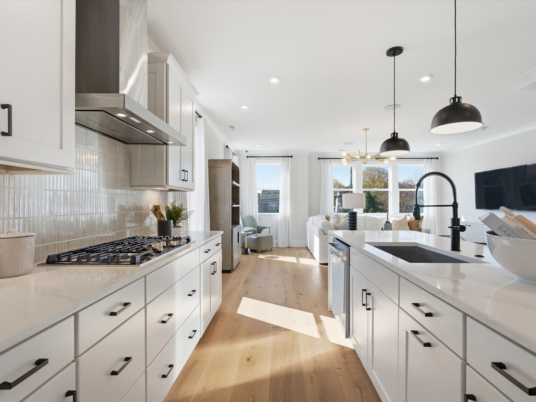 A modern, well-lit kitchen with white cabinets, stainless steel appliances, and a wooden floor, creating a bright and spacious atmosphere.