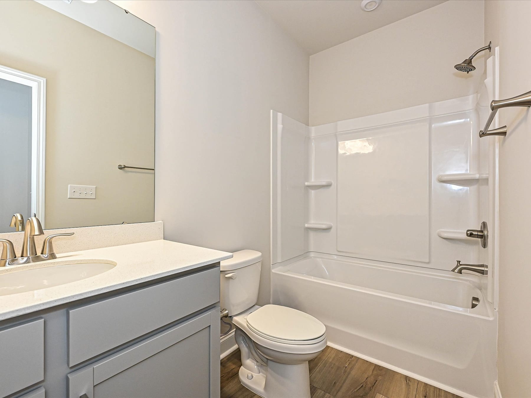 A modern bathroom with a gray vanity, white walls, and a bathtub with a shower curtain.