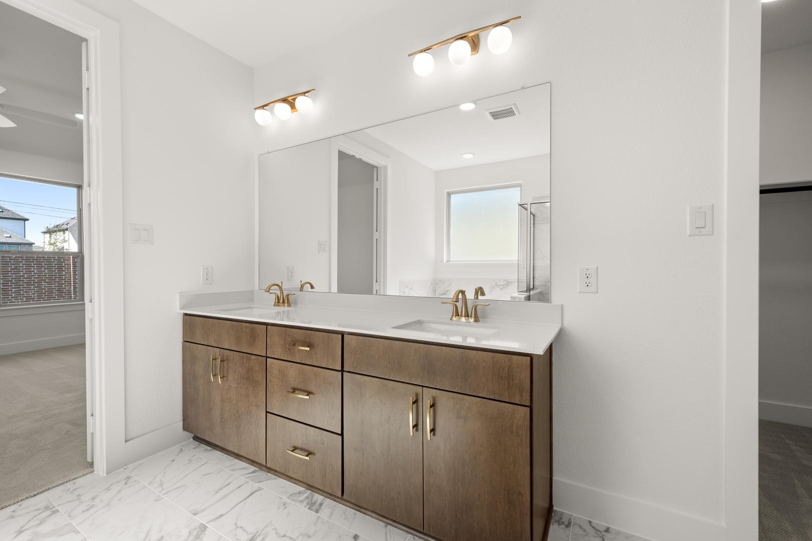 A modern bathroom vanity with a double sink, wooden cabinets, and a large mirror against a white wall backdrop.