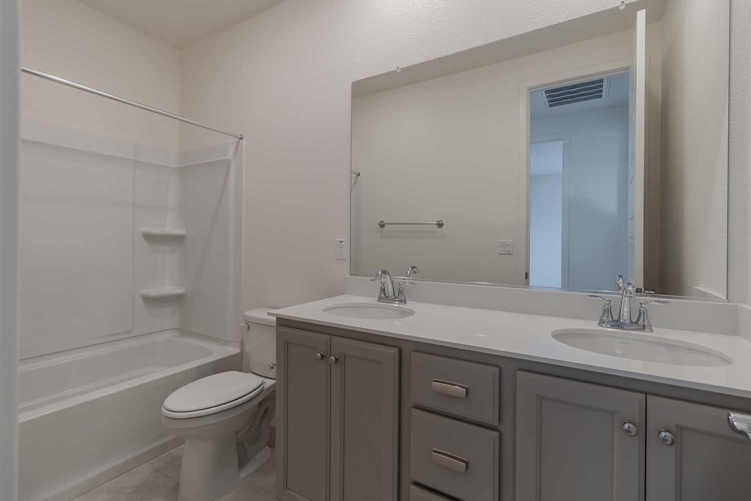 A modern bathroom with a vanity, mirror, and a shower enclosure in the background.