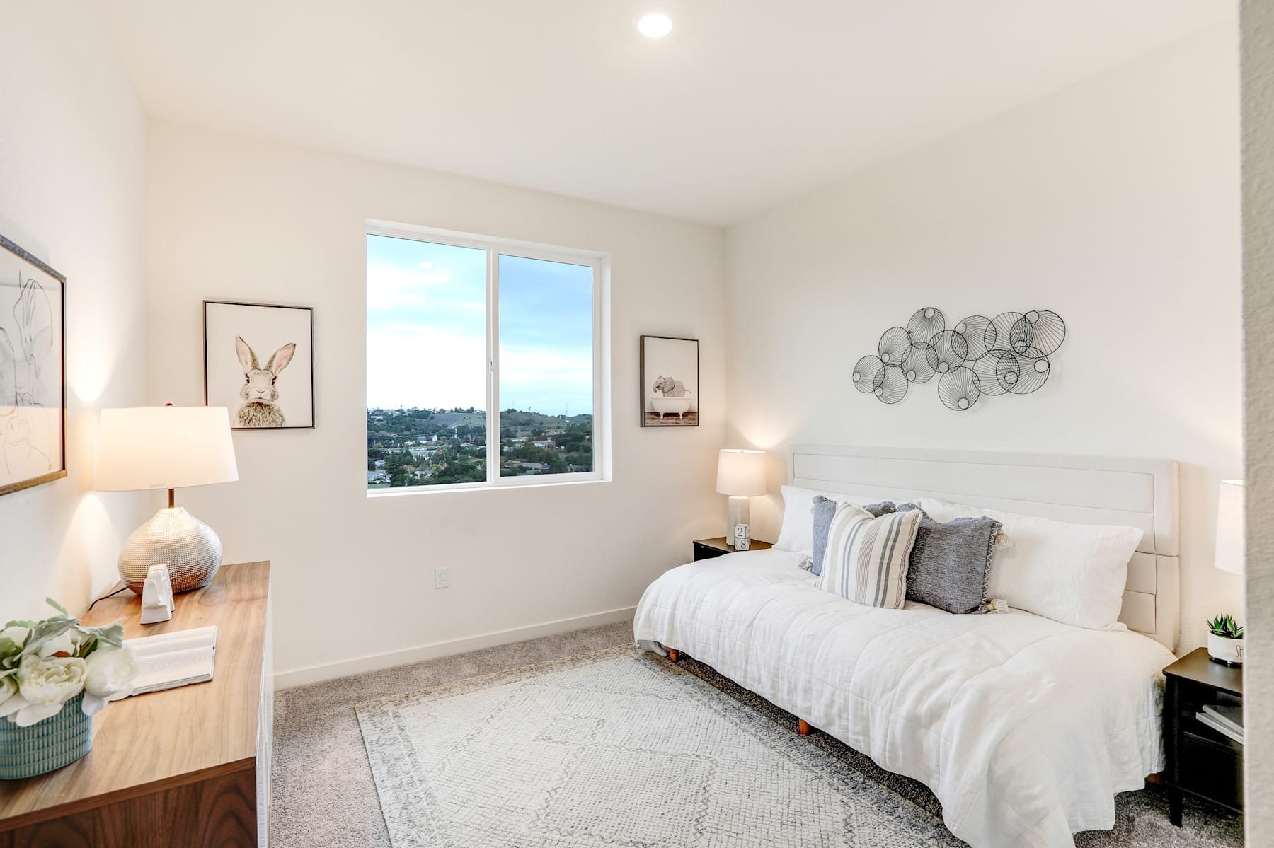 A cozy and well-decorated bedroom with a large window offering a scenic view of the surrounding area.