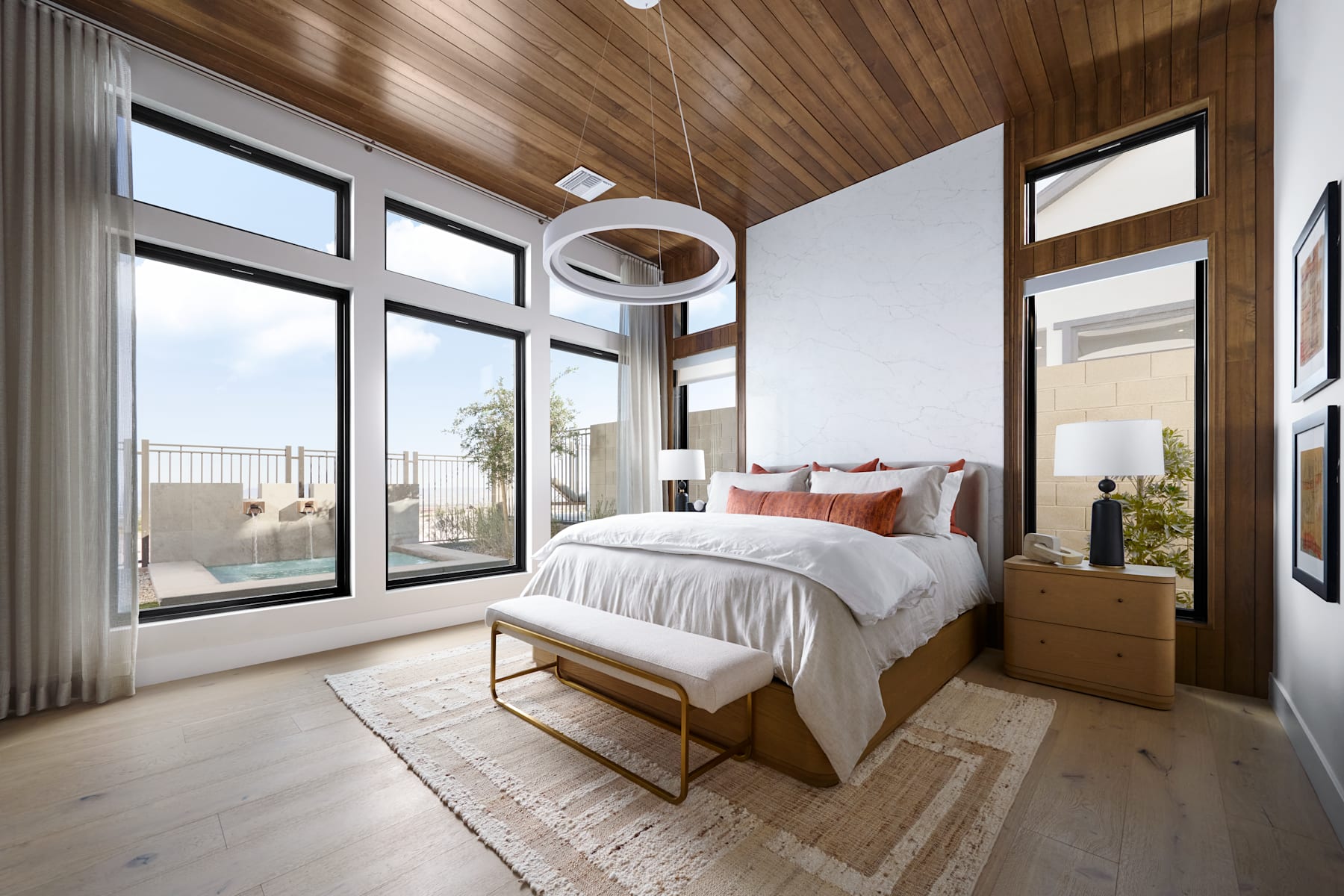A cozy and modern bedroom with large windows, wooden walls, and a plush bed with neutral bedding and accents.