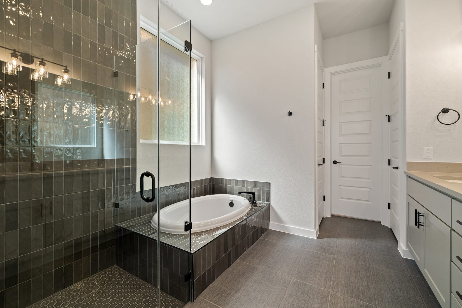 A modern bathroom with a glass-enclosed shower, a freestanding bathtub, and a white door leading to another room.
