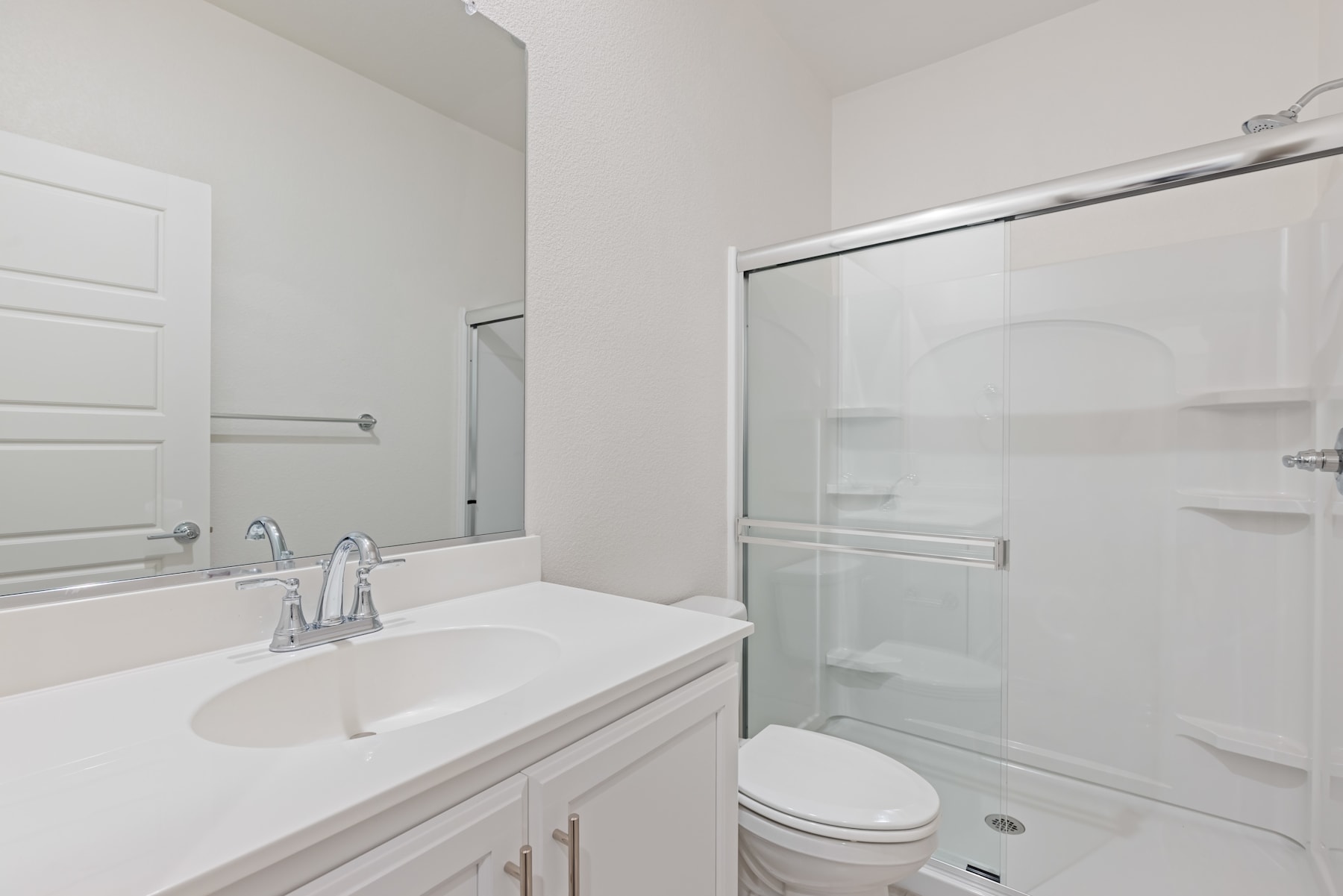 A modern, clean bathroom with a white vanity, sink, and a glass-enclosed shower stall.