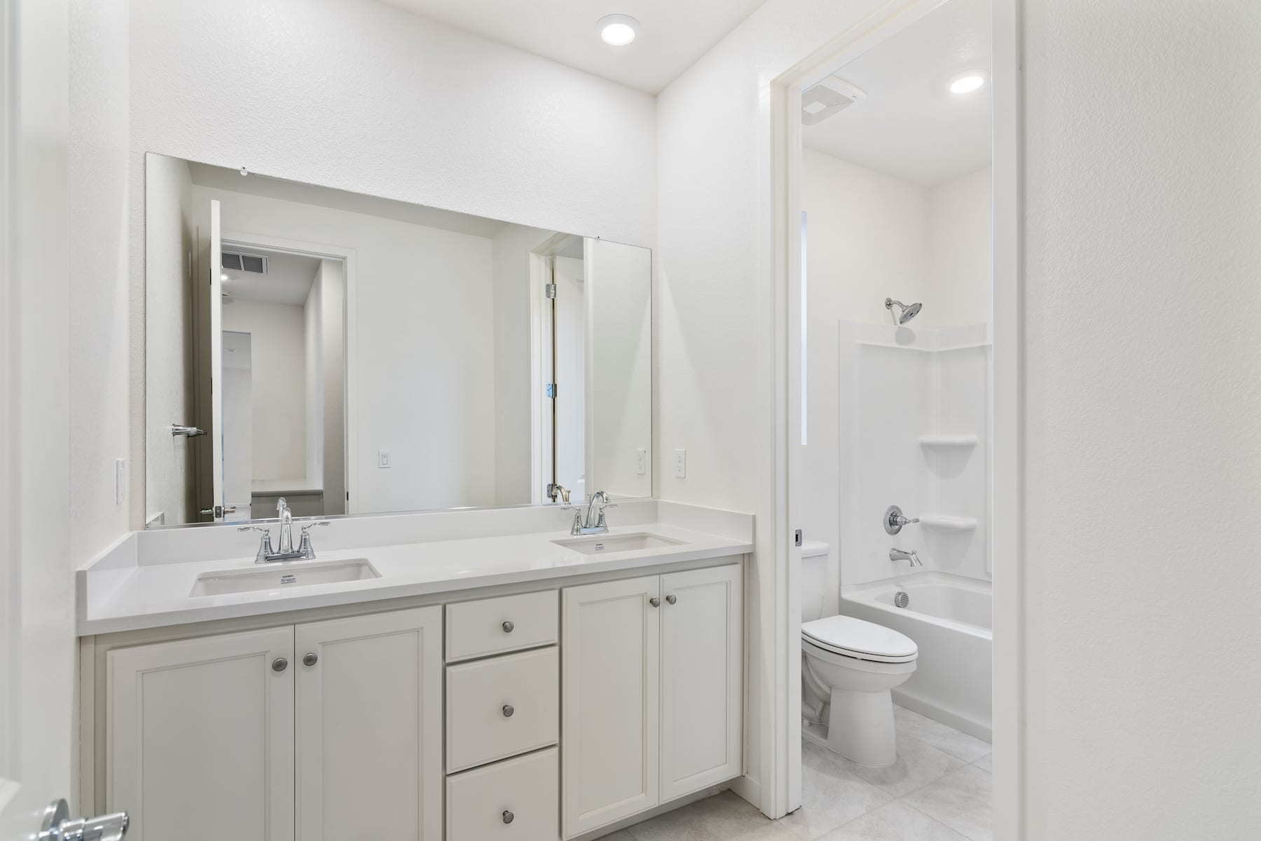 A modern, well-lit bathroom with a vanity cabinet, a large mirror, and a shower enclosure in the background.